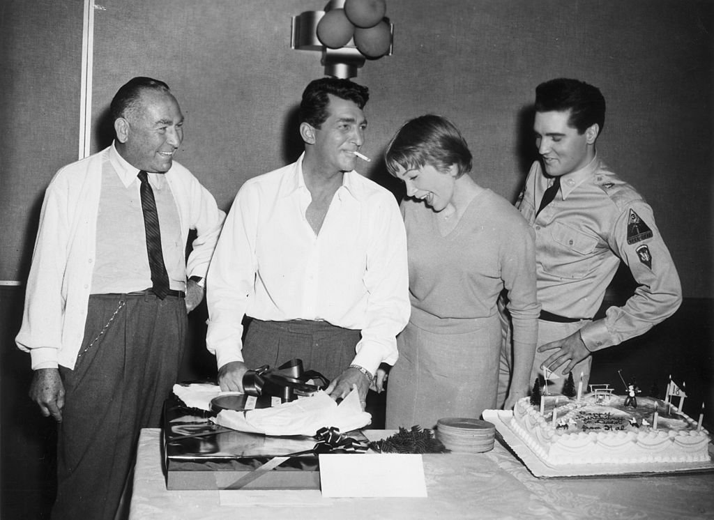  American actor Dean Martin (1917 - 1995, second L), producer Hal Wallis (L), actor Shirley MacLaine, and singer and actor Elvis Presley (1935 - 1977), while in production for director Joseph Anthony's film, 'All in a Night's Work'. | Source: Getty Images