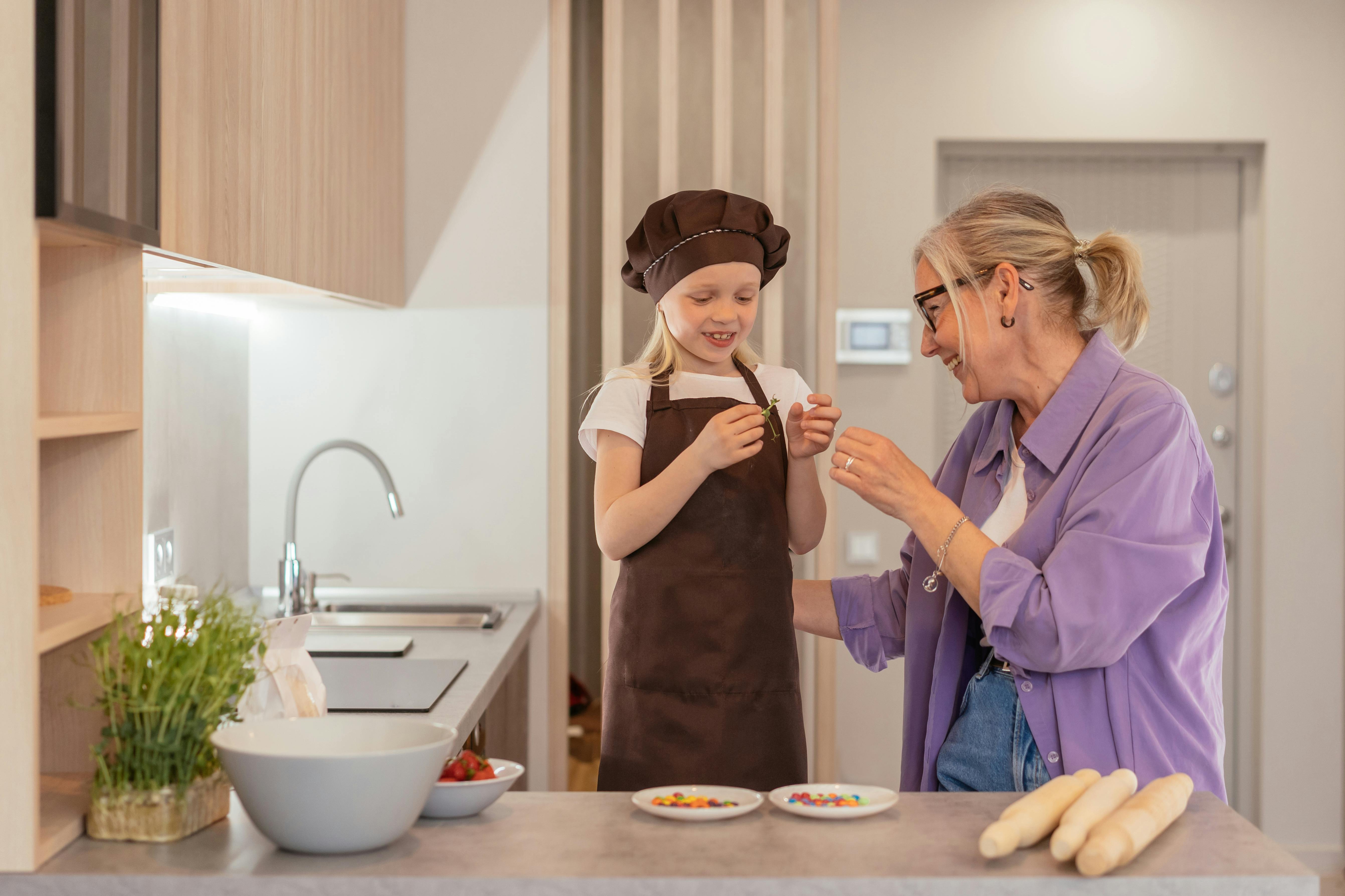A happy woman in the kitchen with her grandchild | Source: Pexels