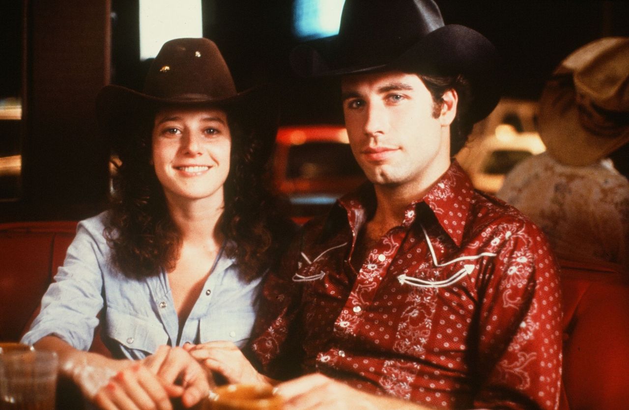 John Travolta and Debra Winger smile on set of the Paramount Pictures movie 'Urban Cowboy" circa 1980. | Source: Getty Images