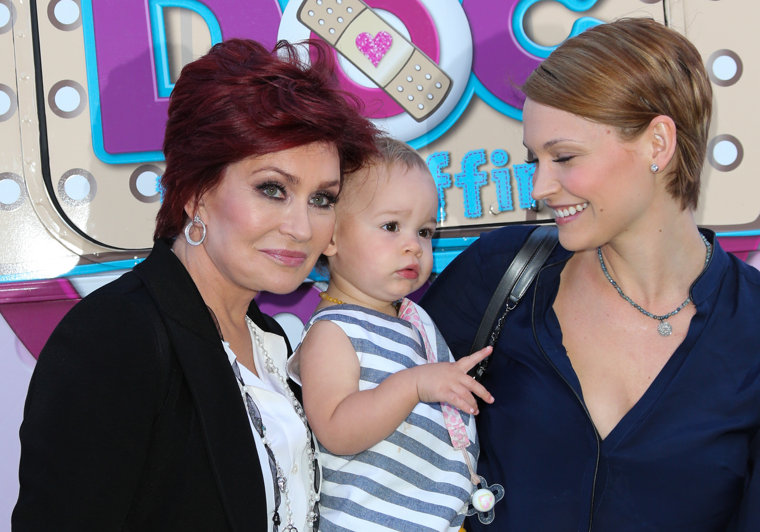 Sharon Osbourne, granddaughter Pearl and daughter-in-law Lisa Stelly attend Disneys Juniour's "Doc McStuffins Doc Mobile" at The Grove on 26 September 2013 in Los Angeles, California. | Source: Getty Images