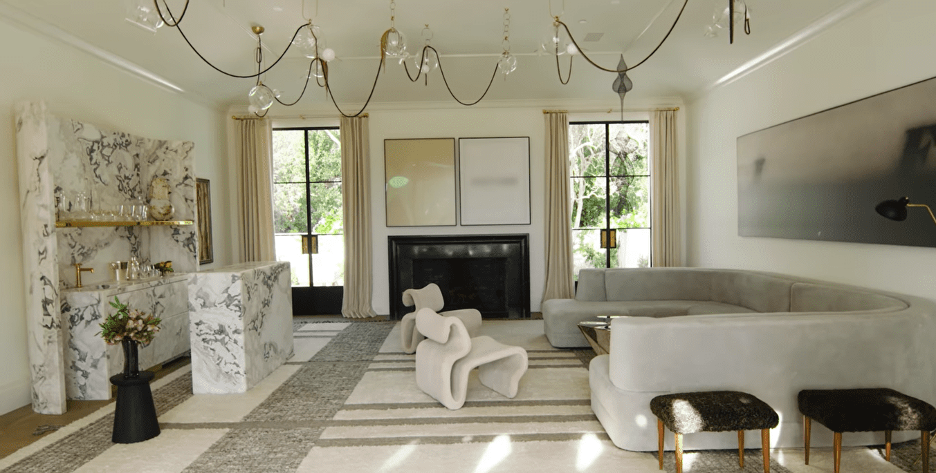 Gwyneth Paltrow's tranquil living room featuring a gray U-shaped couch matching with a large white and gray carpet. / Source: YouTube.com/architecturaldigest