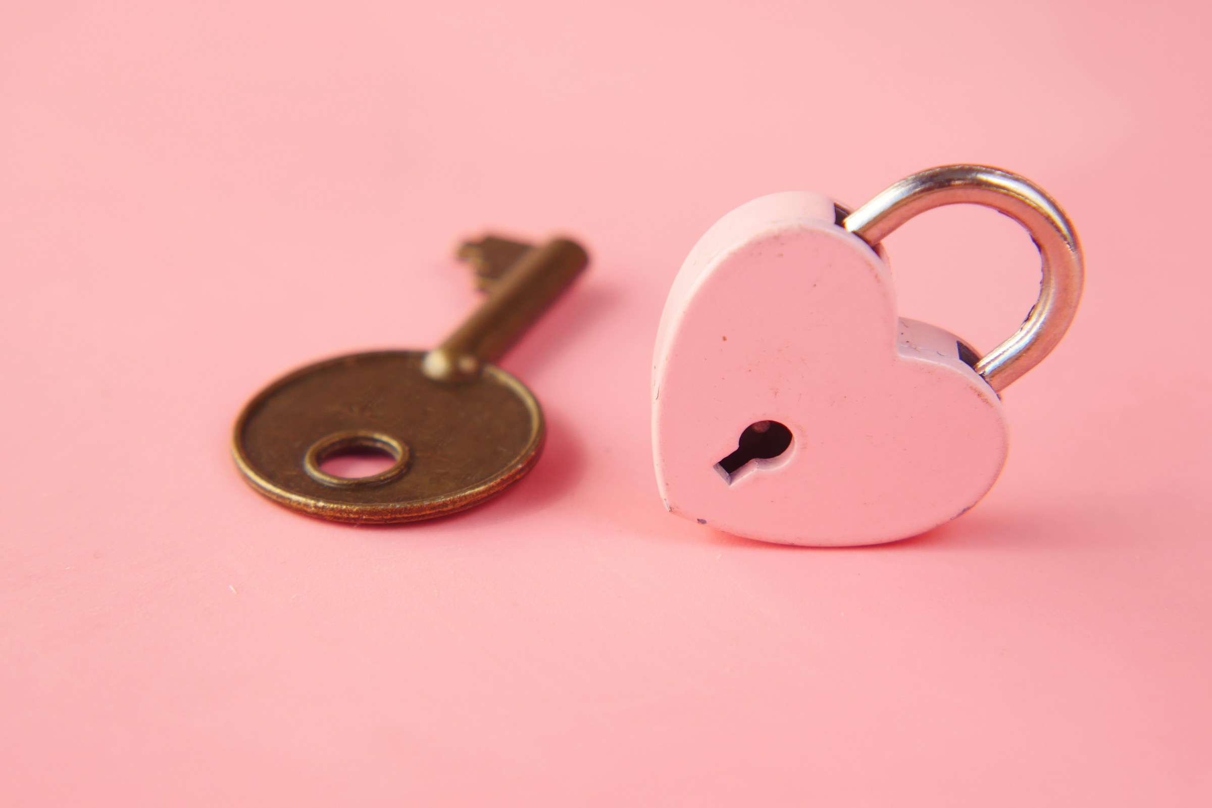 A heart-shaped lock and key on a pink background | Source: Unsplash