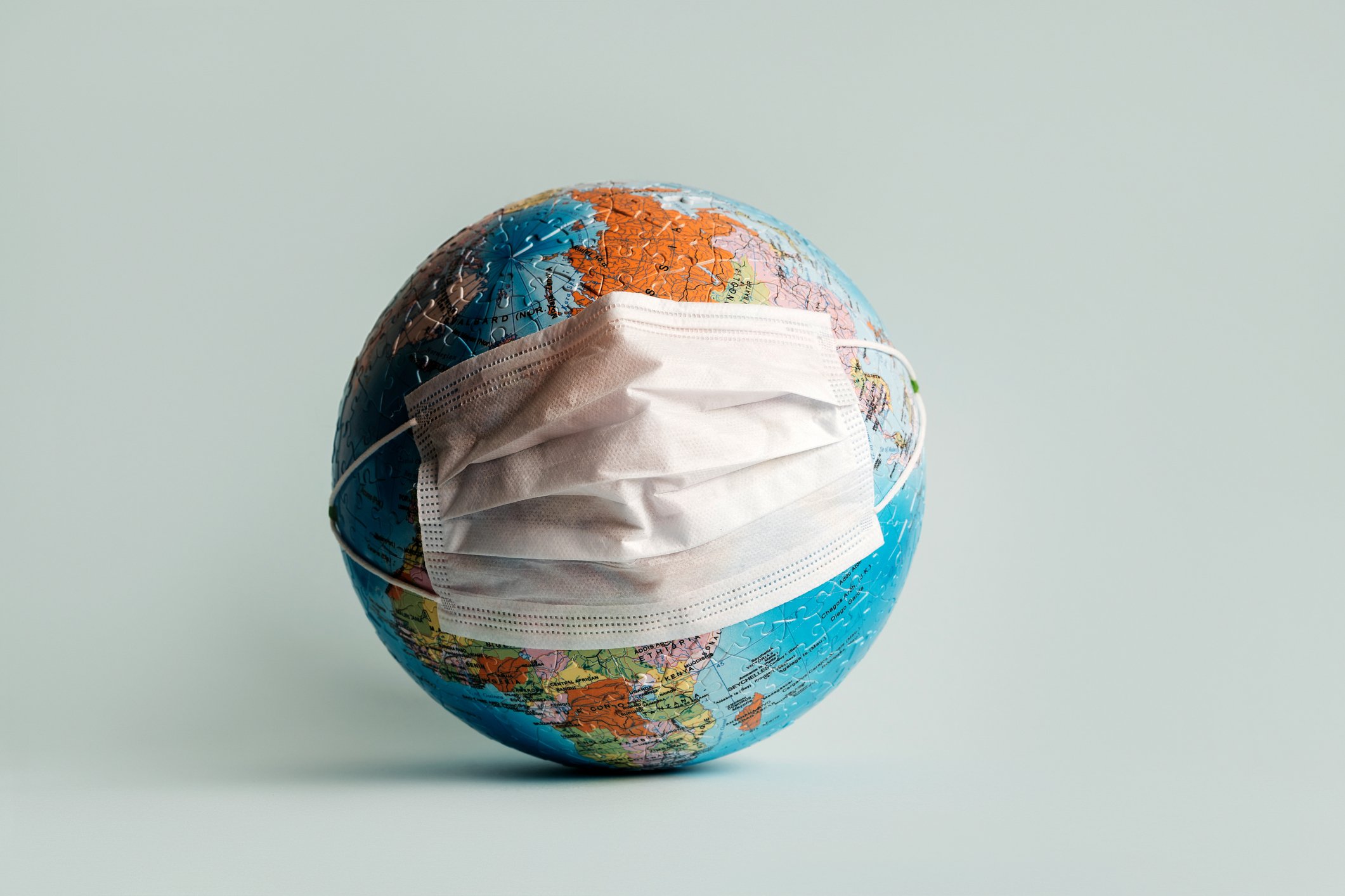 Globus aus Puzzles mit medizinischer Schutzmaske. | Quelle: Getty Images