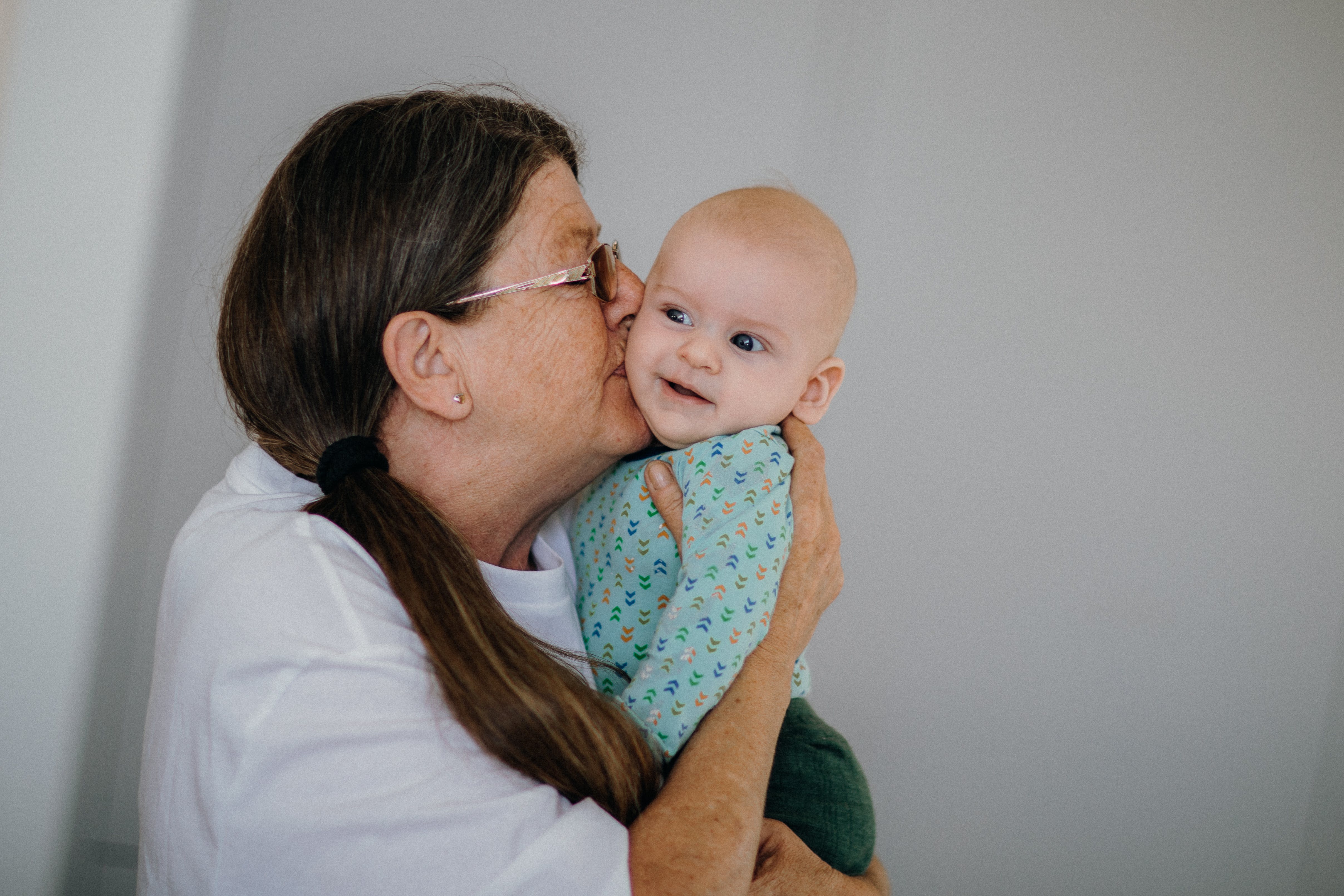 An older woman cradling and kissing an infant on the cheek | Source: Pexels