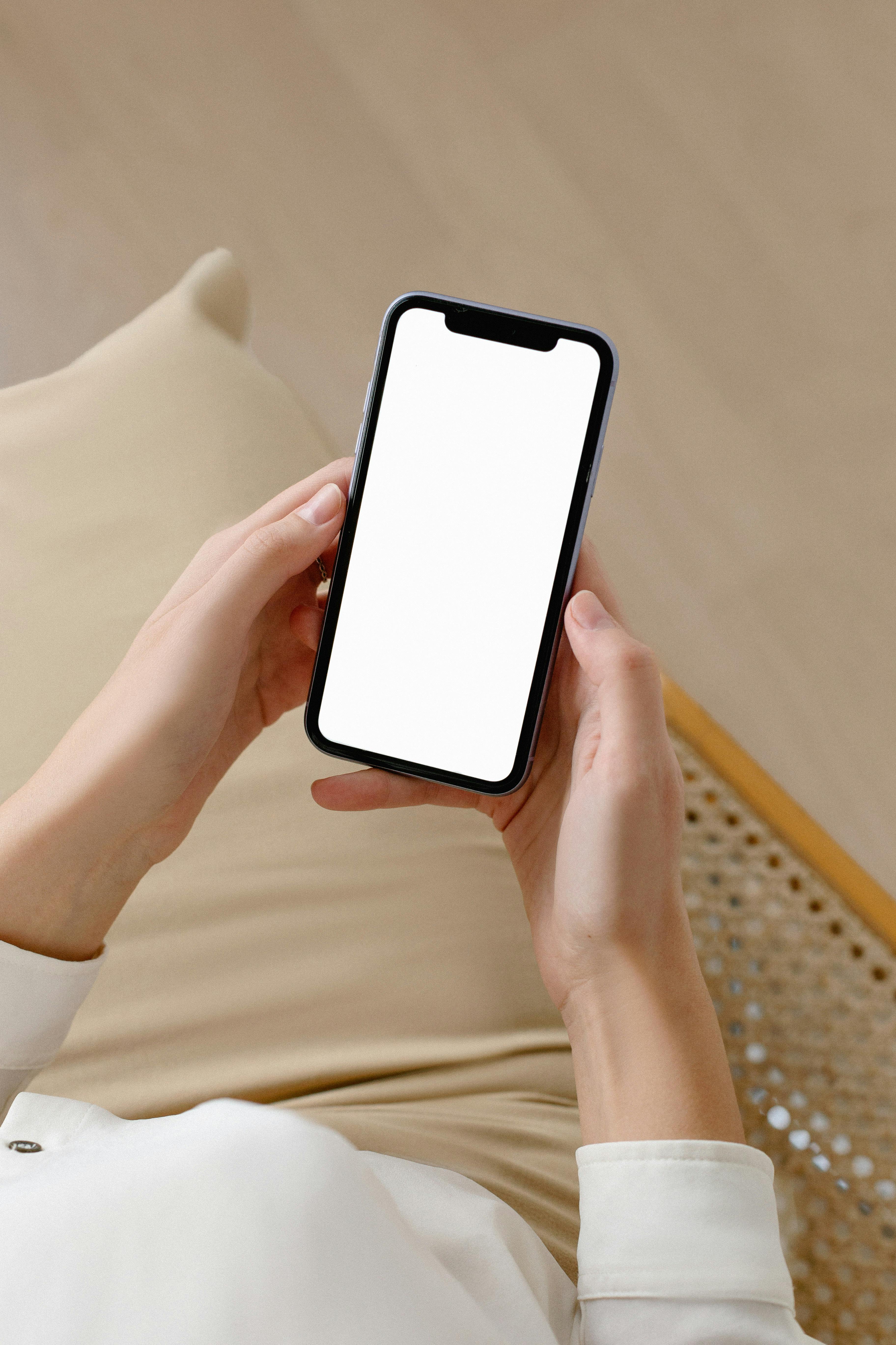 A woman holding up a phone displaying a blank screen | Source: Pexels