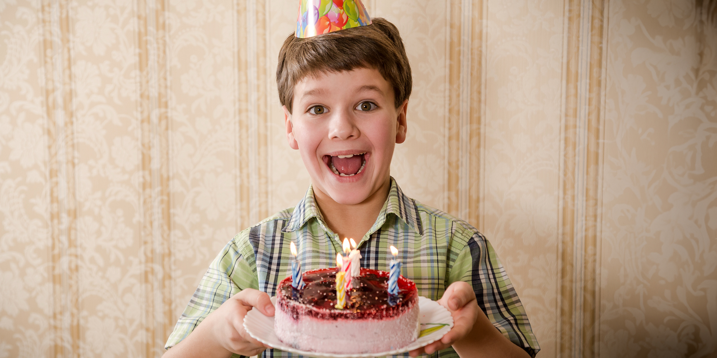 A boy holding a birthday cake | Source: Shutterstock