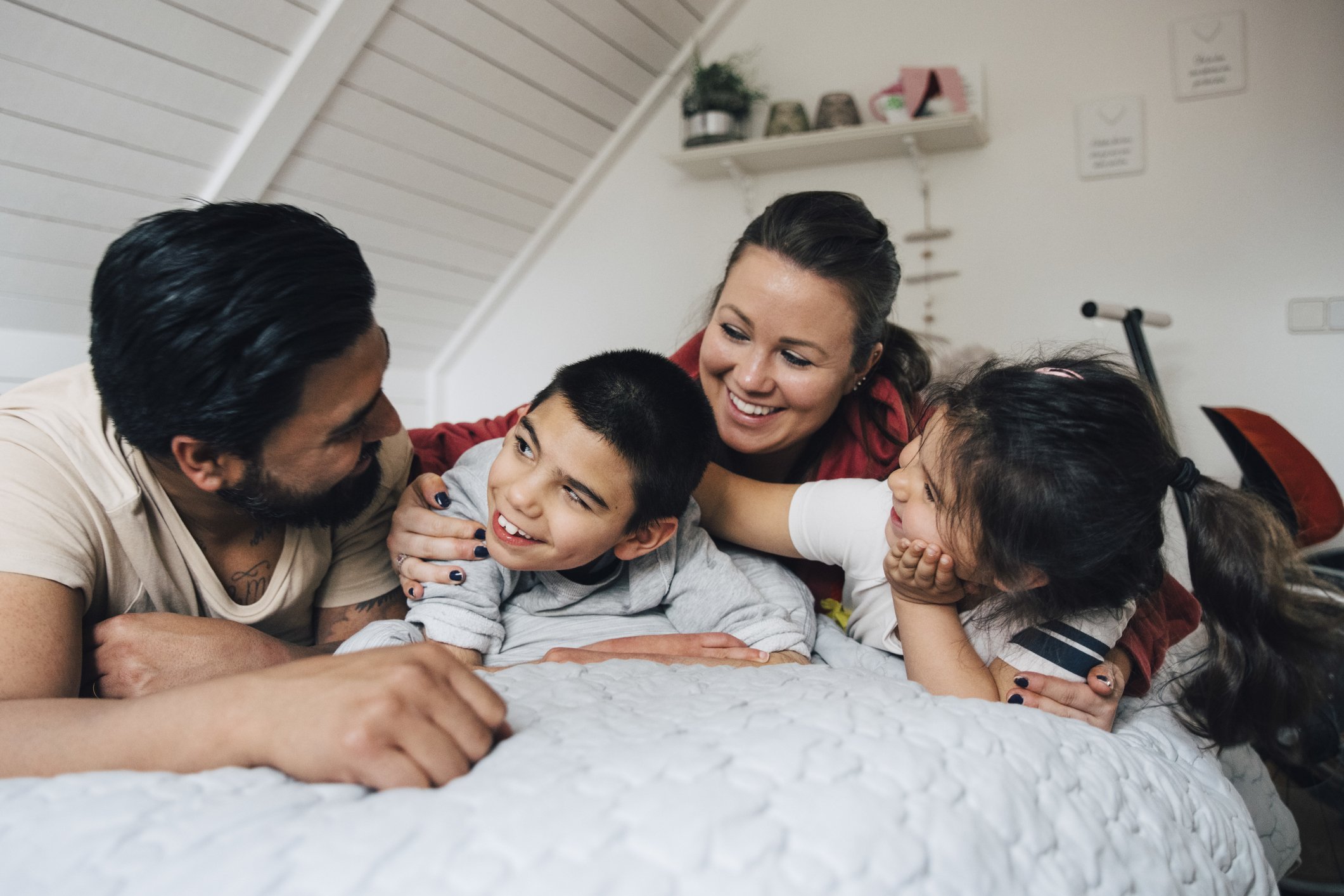 Happy family talking while lying on bed at home |Photo: Getty Images