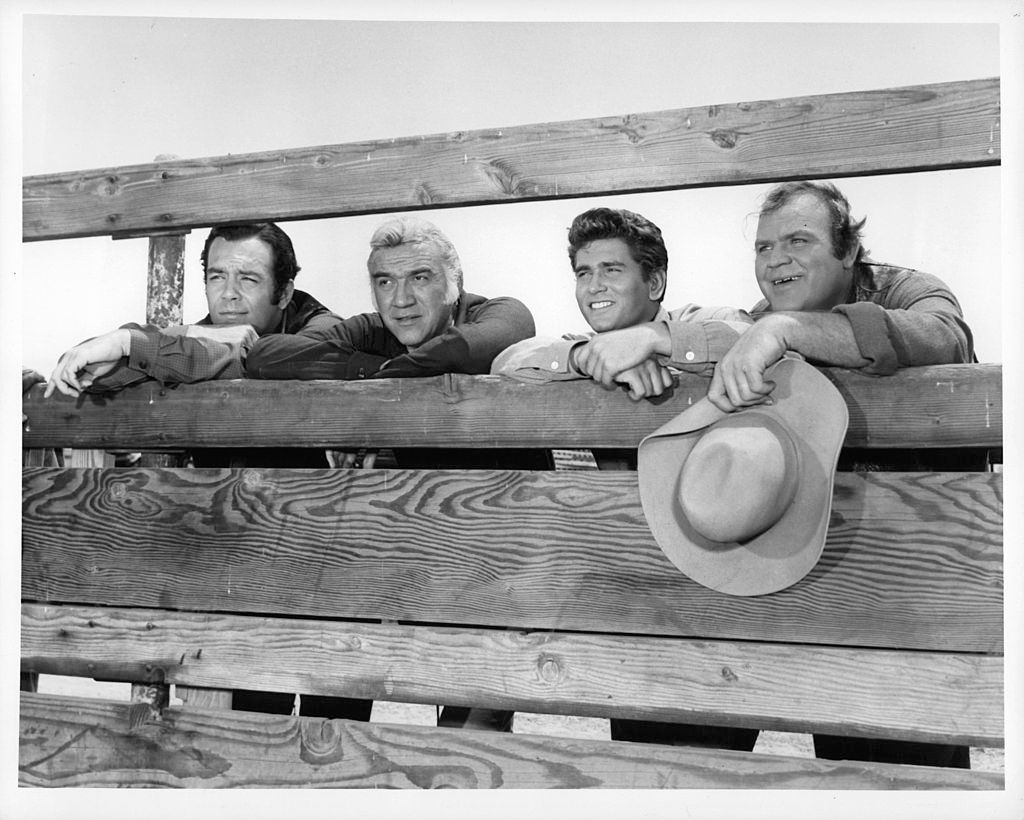 Dan Blocker hält einen Hut und steht mit anderen in einer Szene aus 'Bonanza', 1959-1973. | Foto von National Broadcasting Company/Getty Images