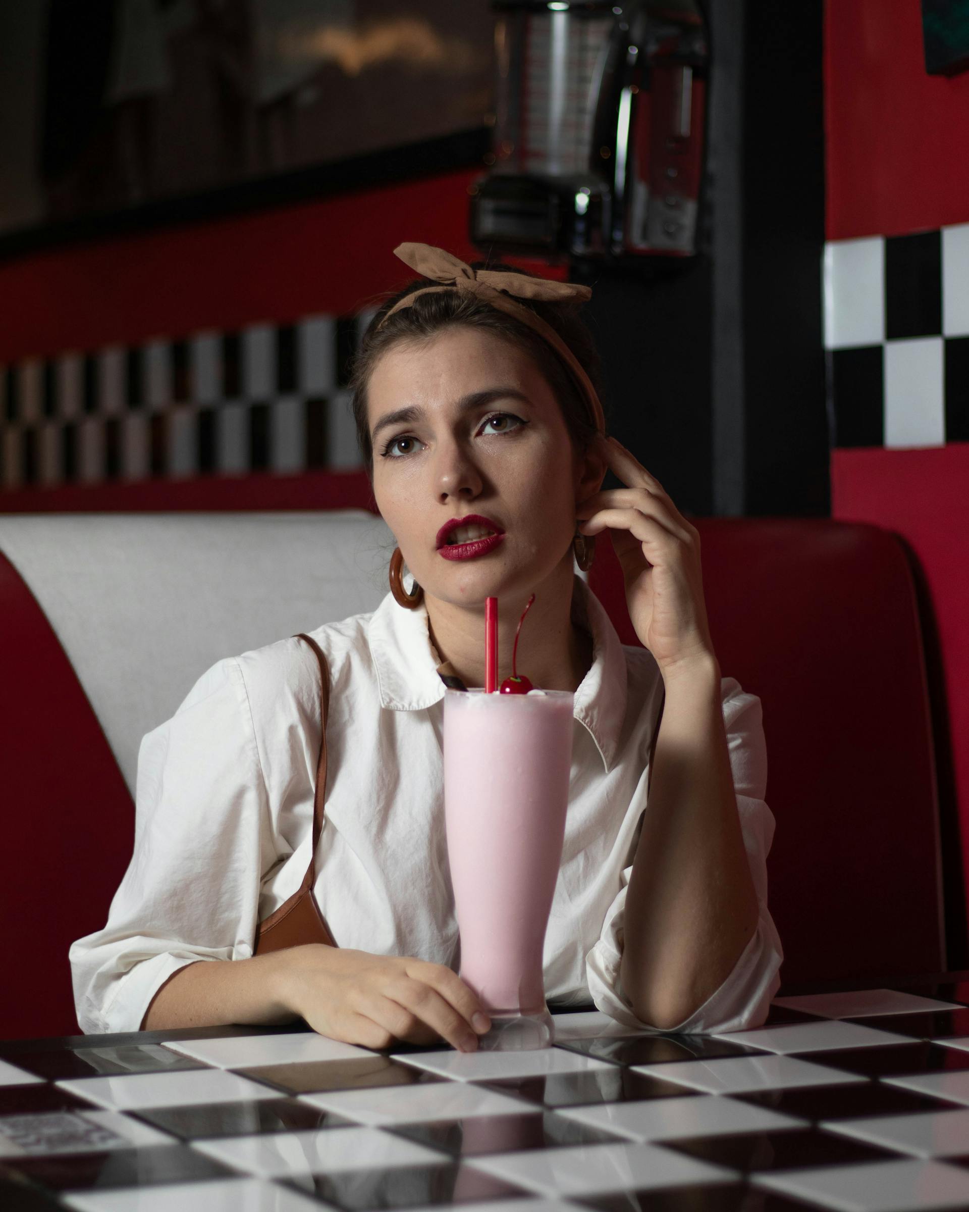 A woman with a glass of strawberry milkshake sitting in a diner | Source: Pexels
