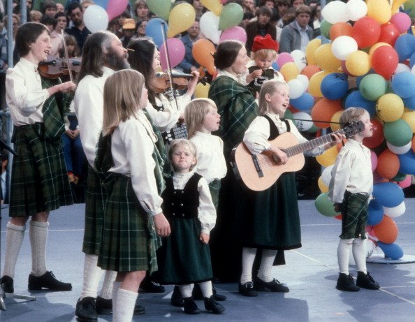 Musikgruppe "Kelly Family" mit Familien-Oberhaupt und Vater Dan Kelly (2.Reihe, 2.v.li., mit Bart), Mutter Barbara-Ann Kelly (2.Reihe, 2.v.re. mit Tochter Maite als Baby- auf Arm), Tochter Kathy (mit Violine.), ; Tochter Patricia (mit Gitarre, 2.v.re.), Sohn Paul (li., mit Geige), Sohn Jimmy und Sohn Joey (vorne, mi.), dazwischen Tochter Barby (zeiht Flunsch), Sohn Paddy (re.), Auftritt Berlin | Quelle: Getty Images
