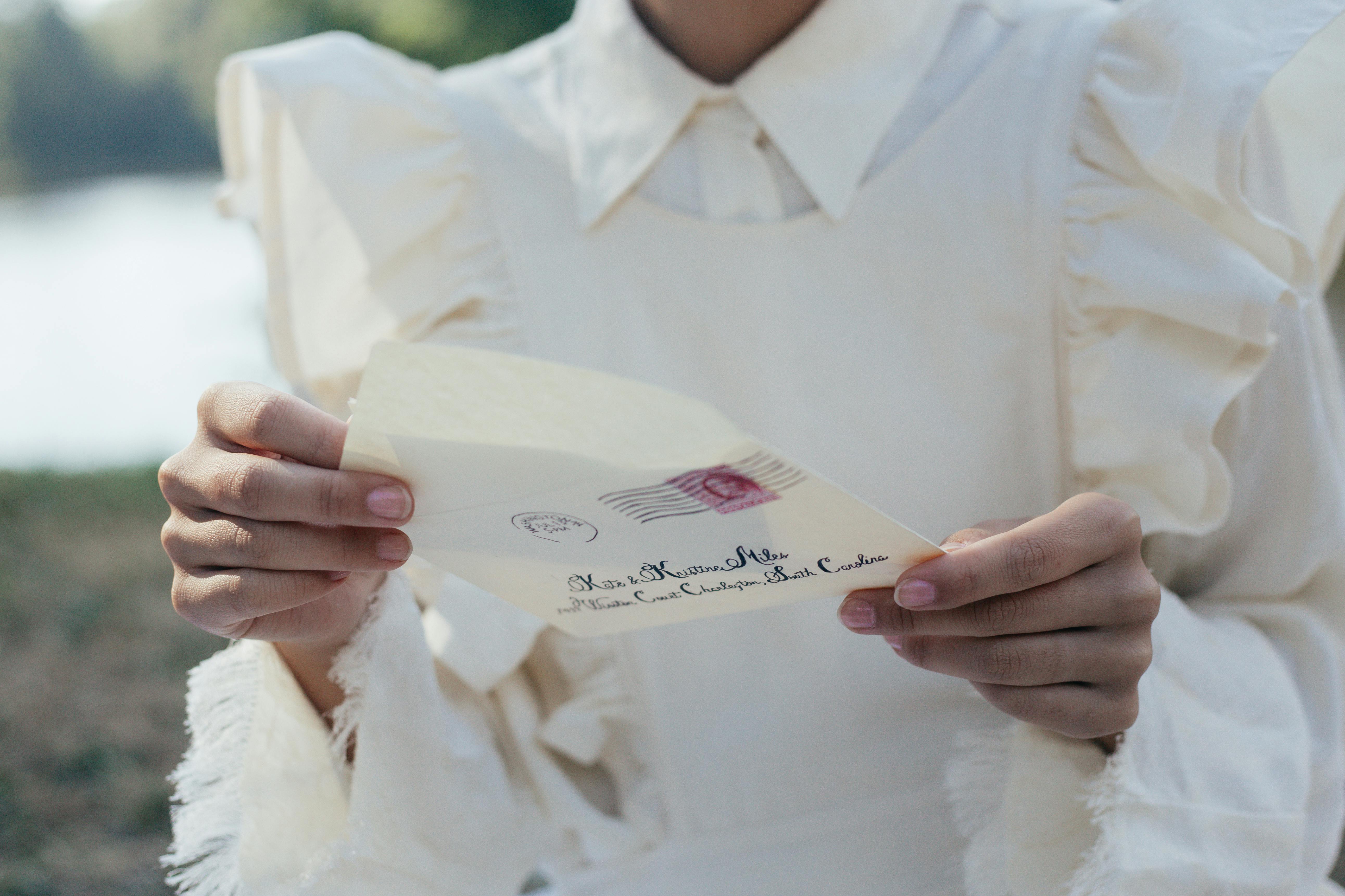 A person in a white dress holding a letter | Source: Pexels