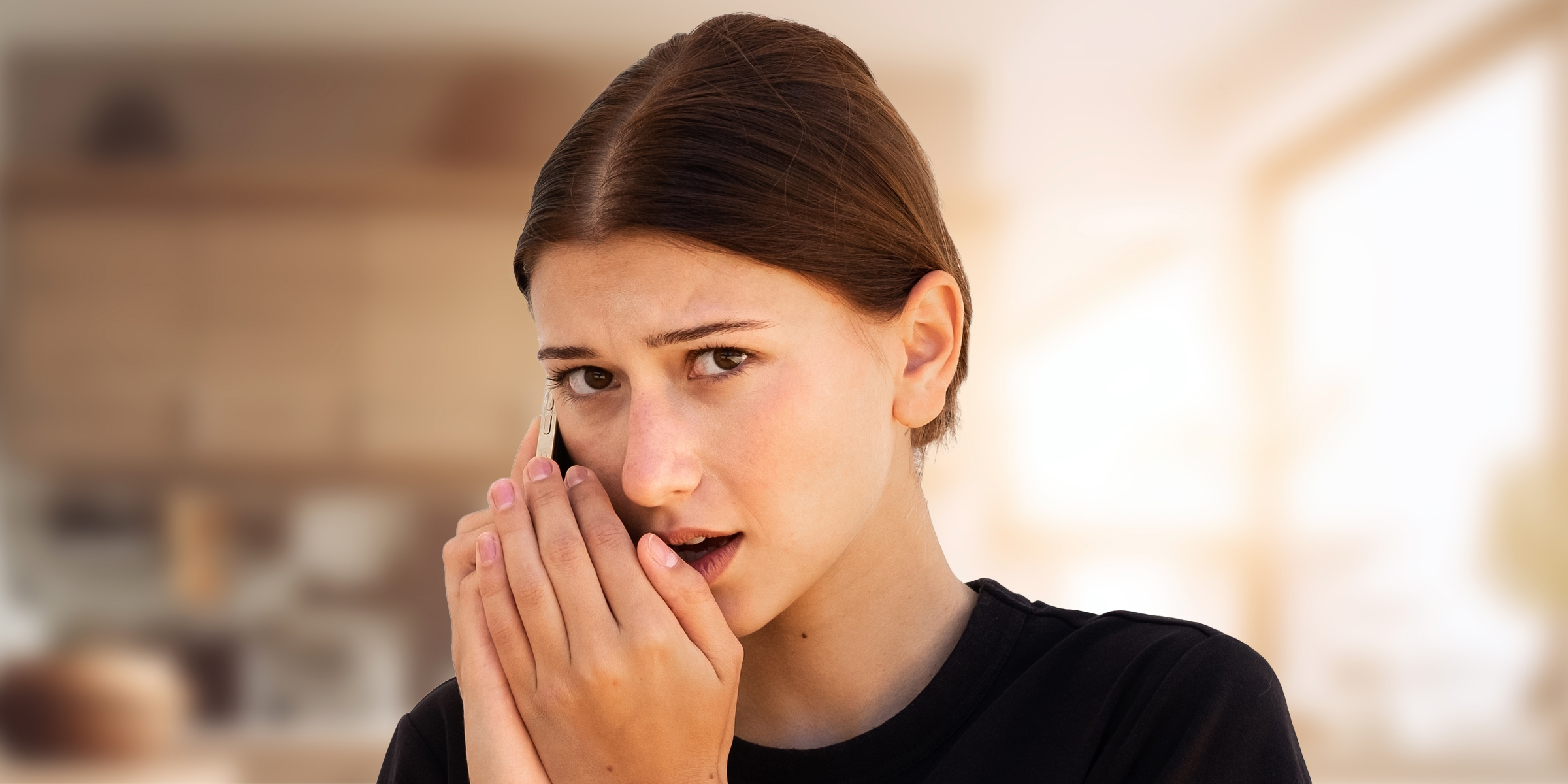 A young woman speaking secretively on her phone | Source: Shutterstock