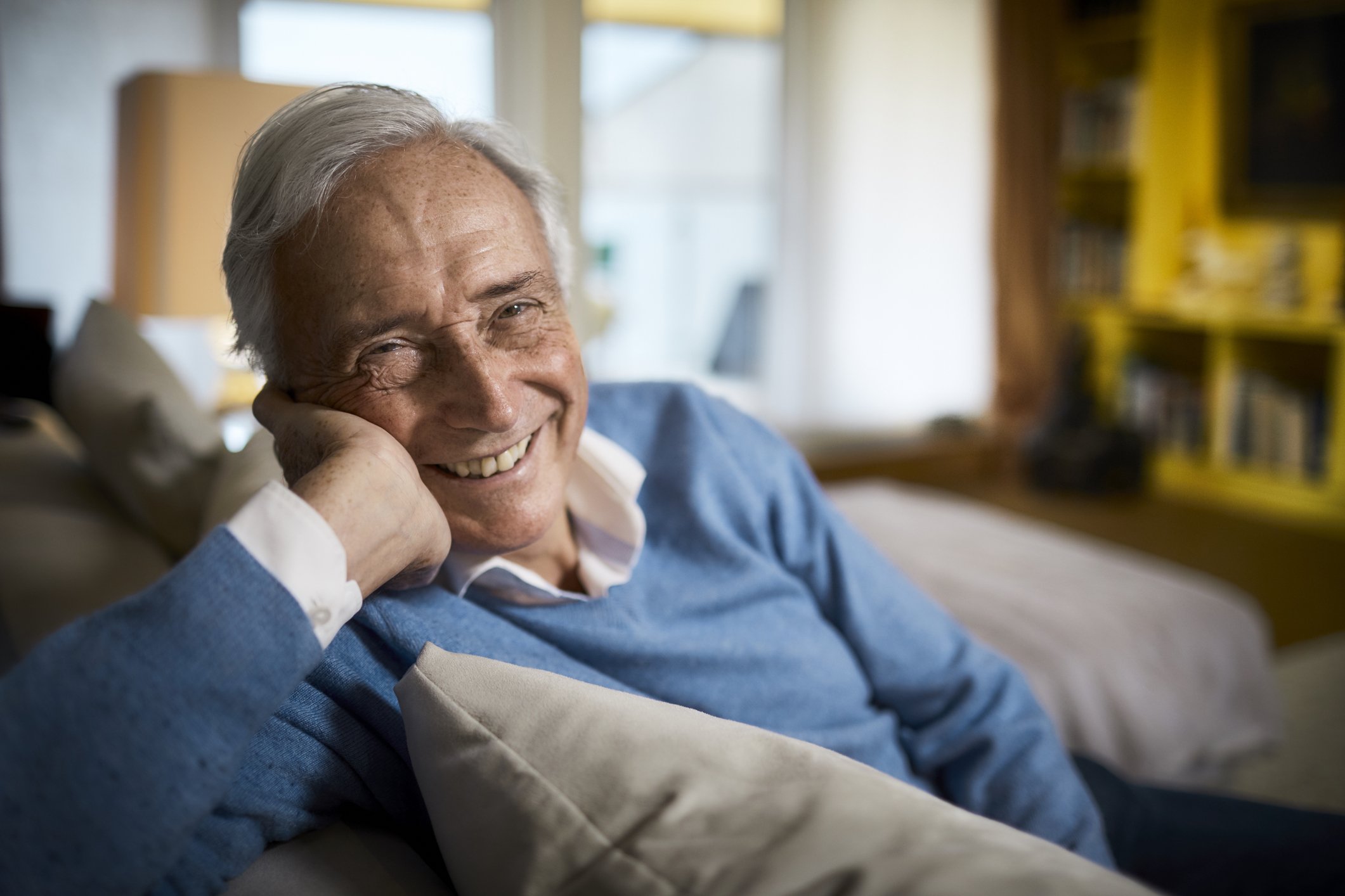 An elderly man grinning from a sofa | Photo: Pexels