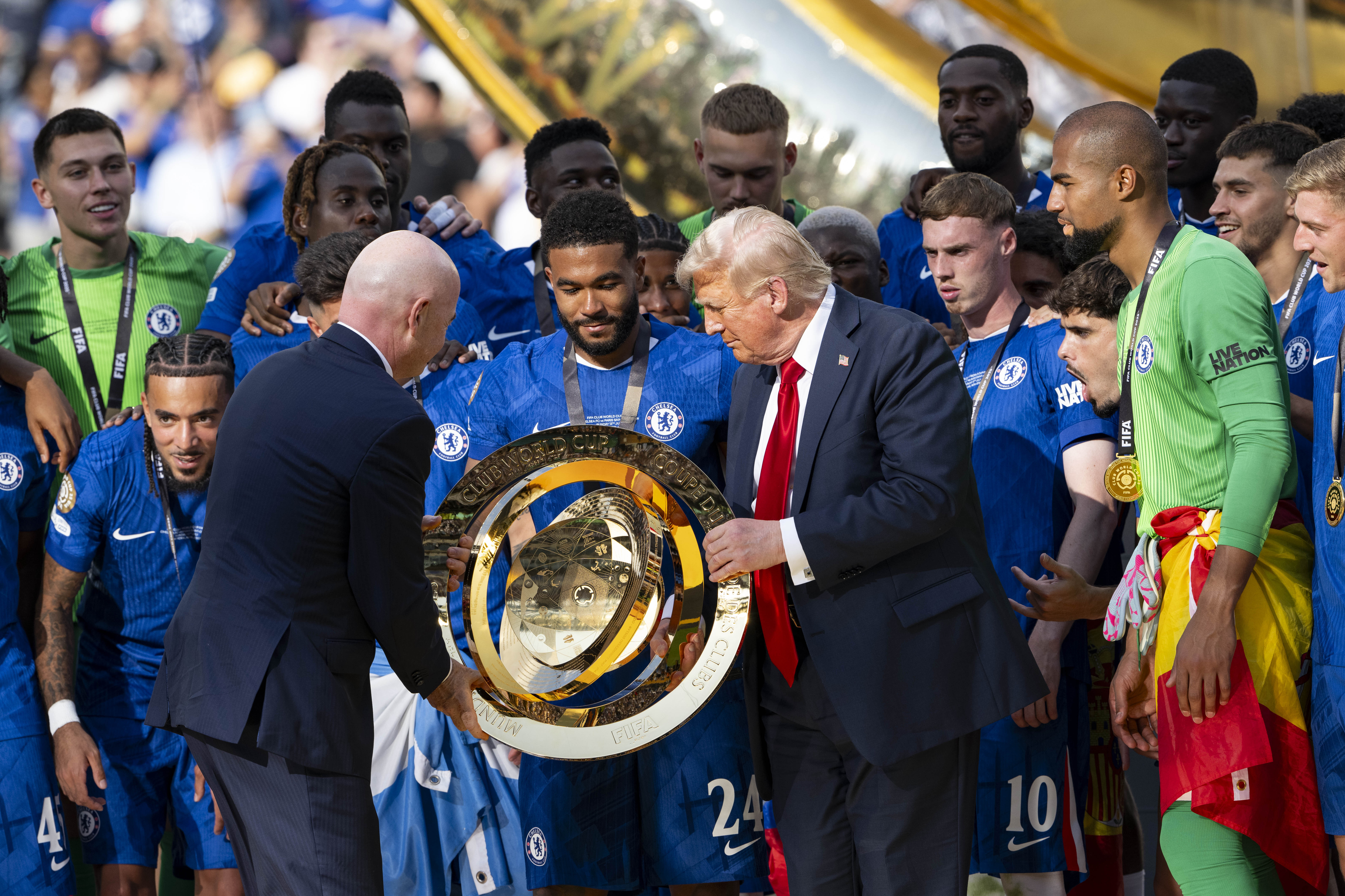 Gianni Infantino and Donald Trump presenting the FIFA Club World Cup trophy to the Chelsea FC players following the FIFA Club World Cup 2025 final on July 13. | Source: Getty Images