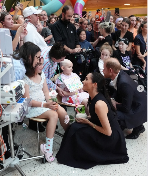 Meghan, Duchess of Sussex, and Prince Harry, Duke of Sussex, knelt beside young patients as they shared a warm exchange during their visit to the Royal Children's Hospital in Melbourne, as seen in a post dated 14 April 2026. | Source: Instagram/hellomag