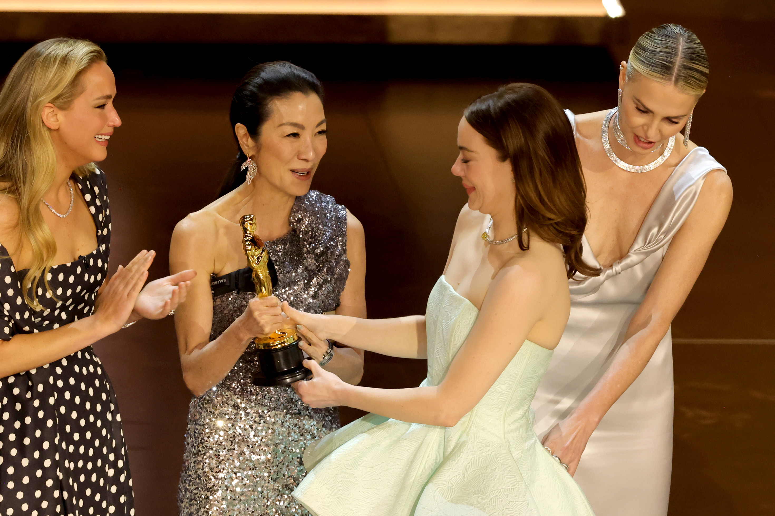Emma Stone accepts the Best Actress in a Leading Role award for "Poor Things" from Jennifer Lawrence, Michelle Yeoh, and Charlize Theron during the 96th Annual Academy Awards on March 10, 2024 in Hollywood, California | Source: Getty Images