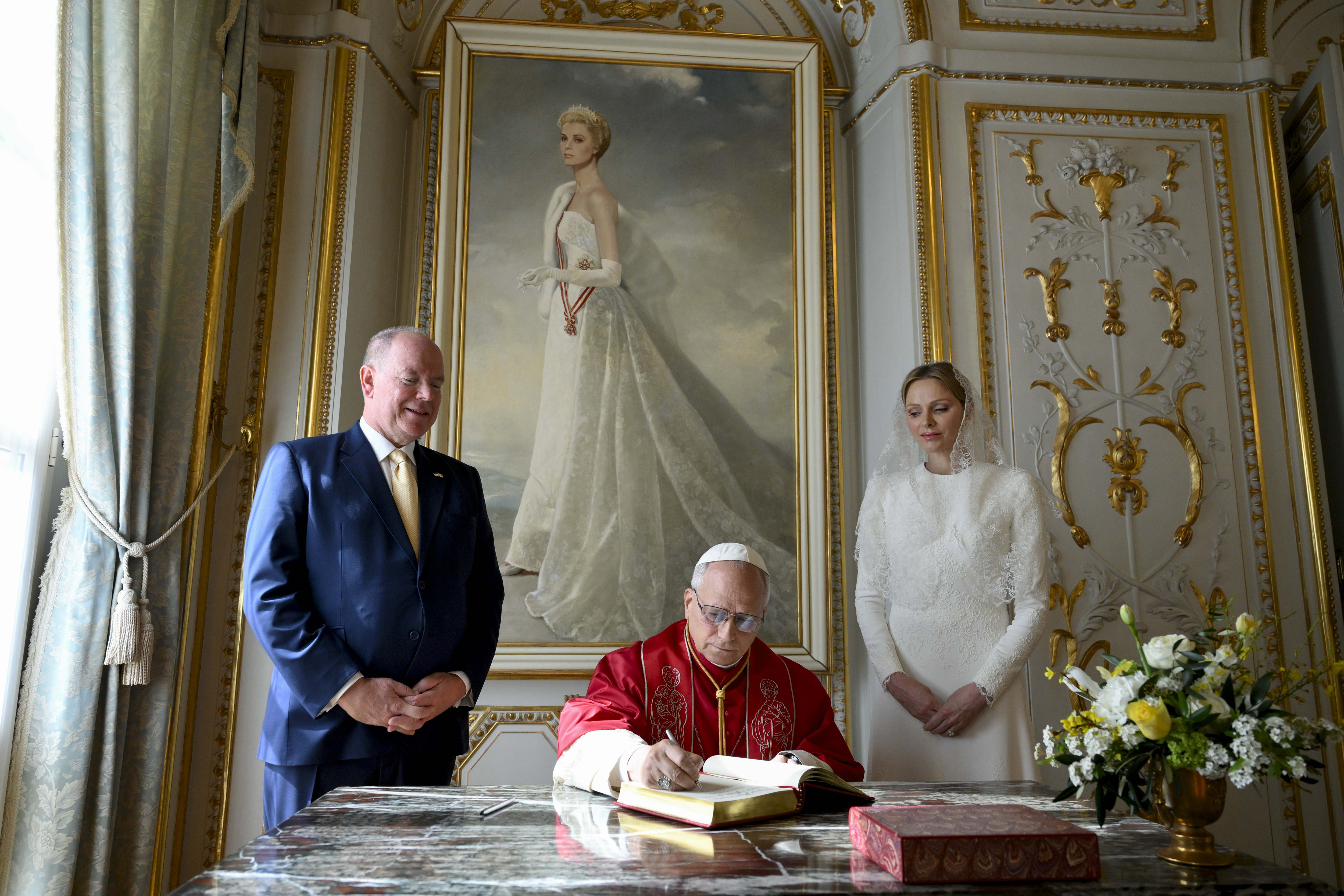 Pope Leo XIV, flanked by Princess Charlene and Prince Albert II of Monaco, signs the book of honor during the visit at the Prince's Palace of Monaco on March 28, 2026 | Source: Getty Images