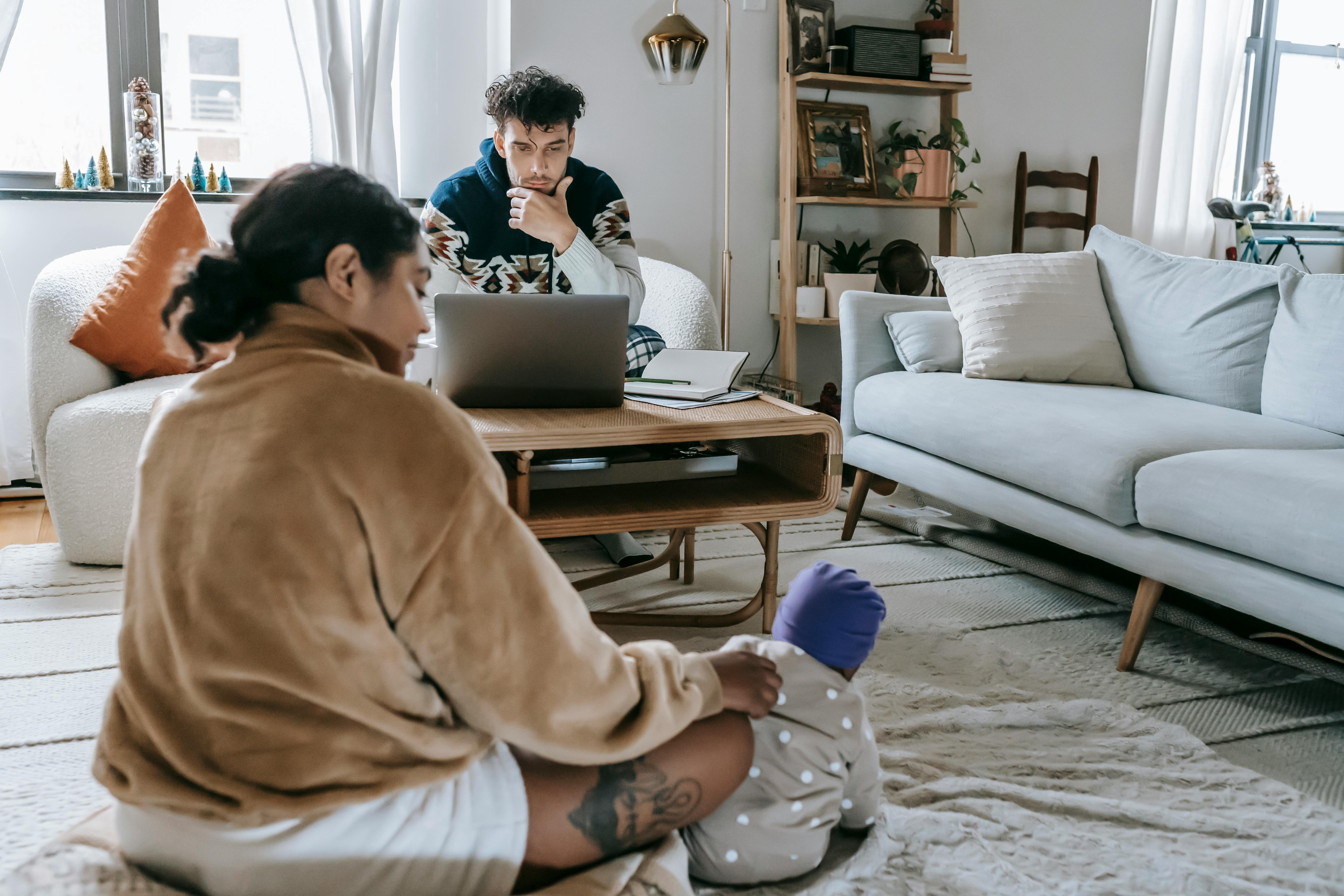 A man busy working while his wife looks after their newborn | Source: Pexels