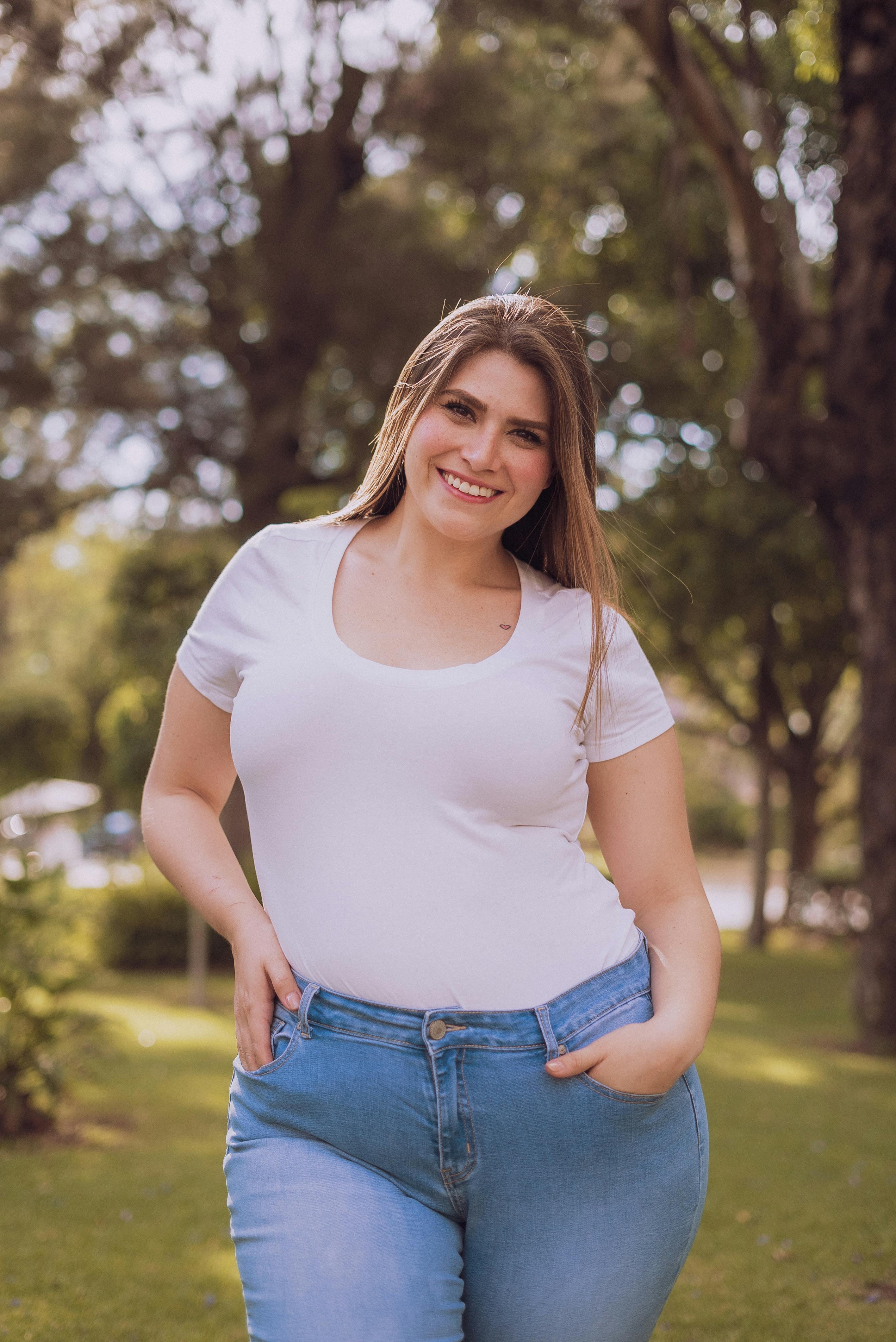 A smiling woman in a white top and jeans | Source: Pexels