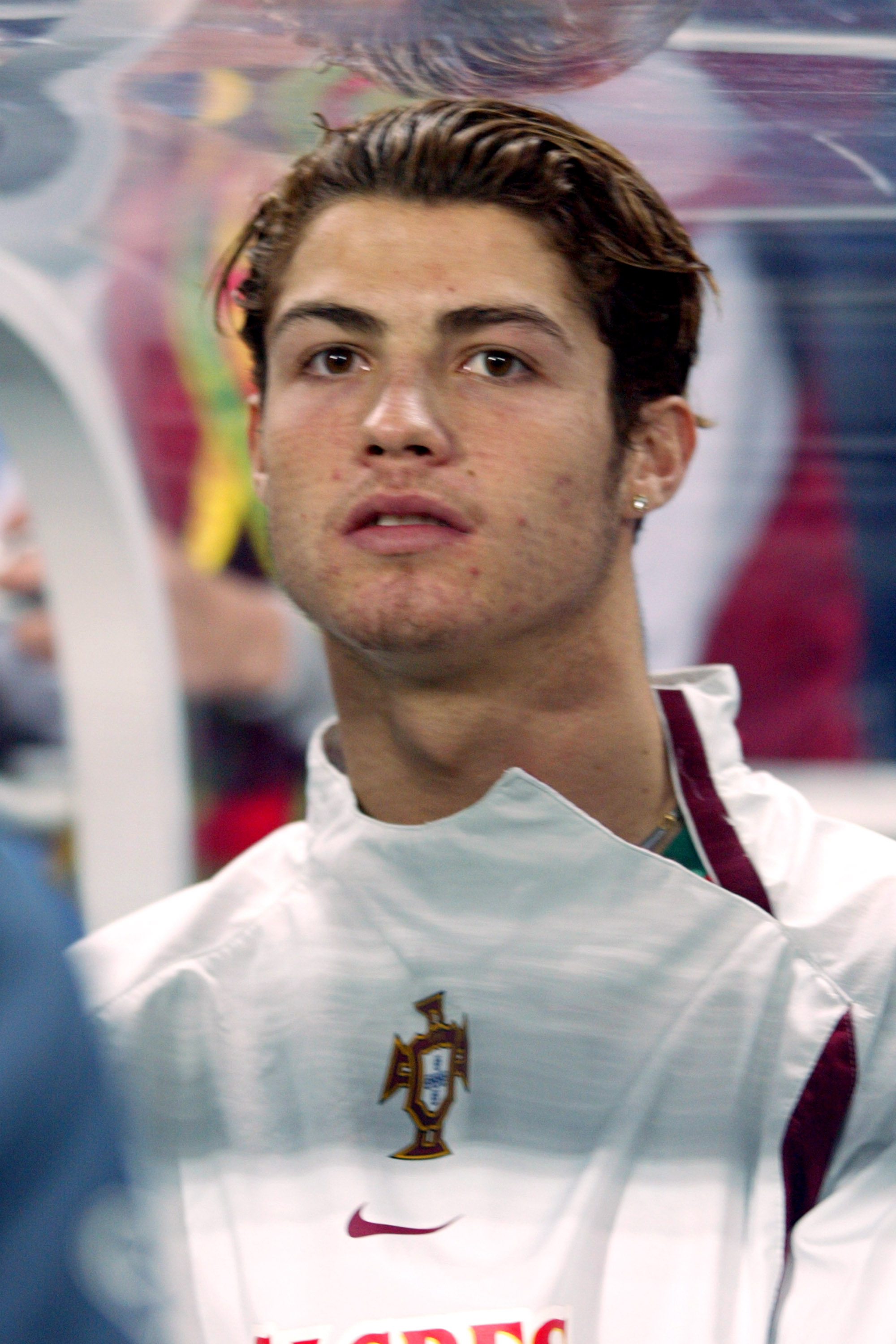 Cristiano Ronaldo waited on the sidelines before Portugal's international friendly against England on February 18, 2004. The close-up captured the rising star early in his international career, showcasing his youthful complexion, natural facial contours, and understated look before the refined appearance that would later become part of his public image.