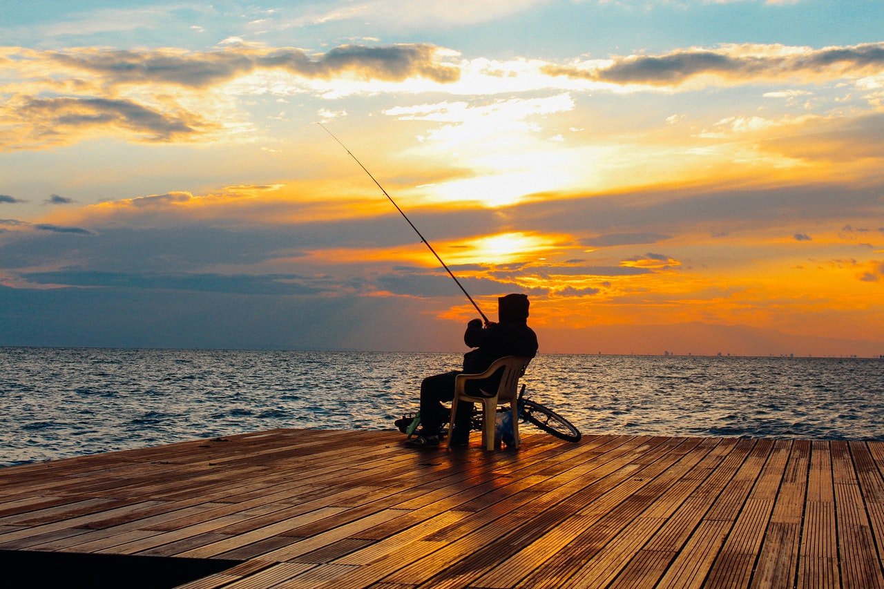 A man enjoying the sunset while fishing | Photo: Pexels