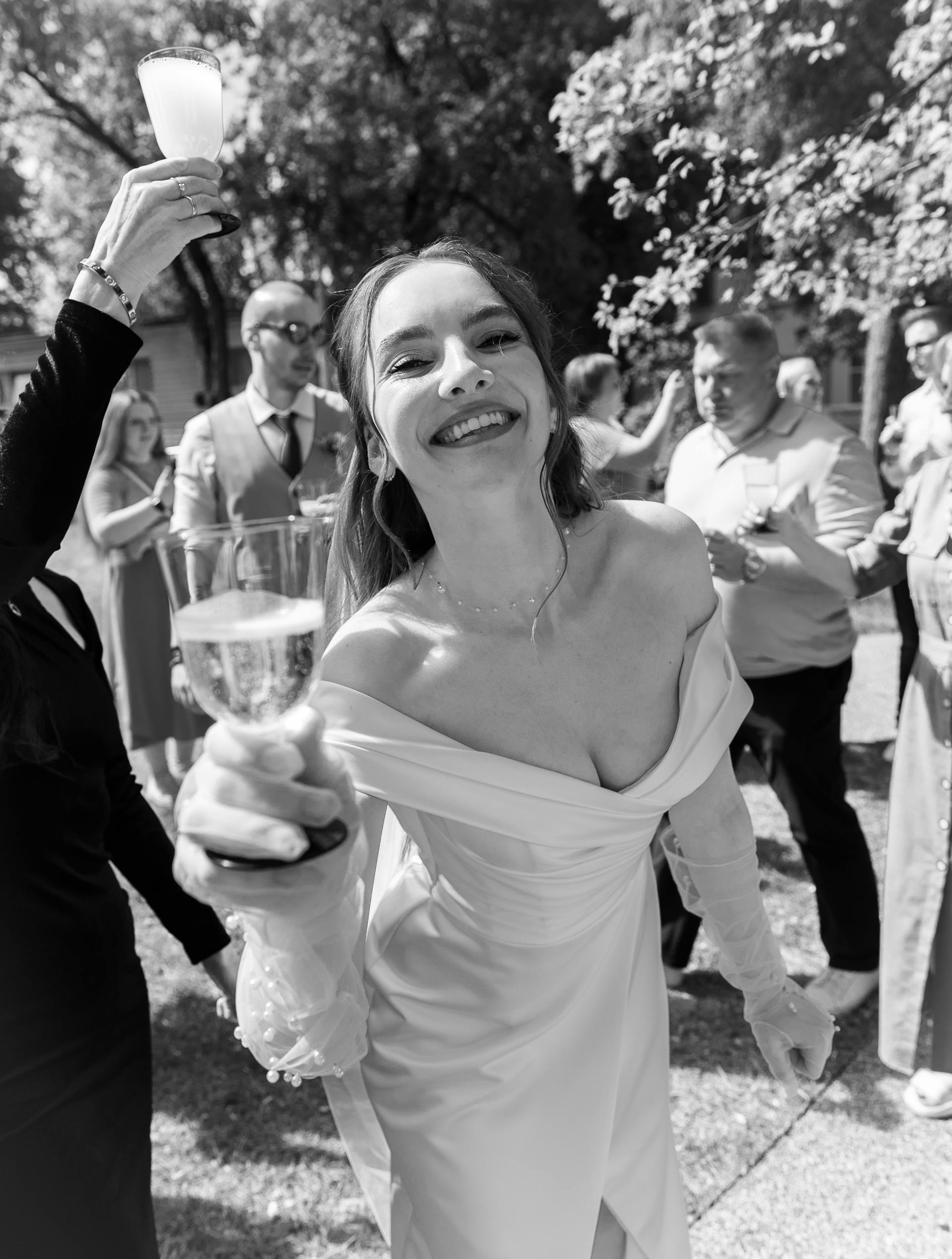 Grayscale shot of a smiling bride with a drink in her hand | Source: Pexels