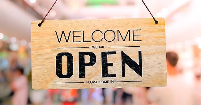 An open sign in front of the door of a store | Photo: Shutterstock