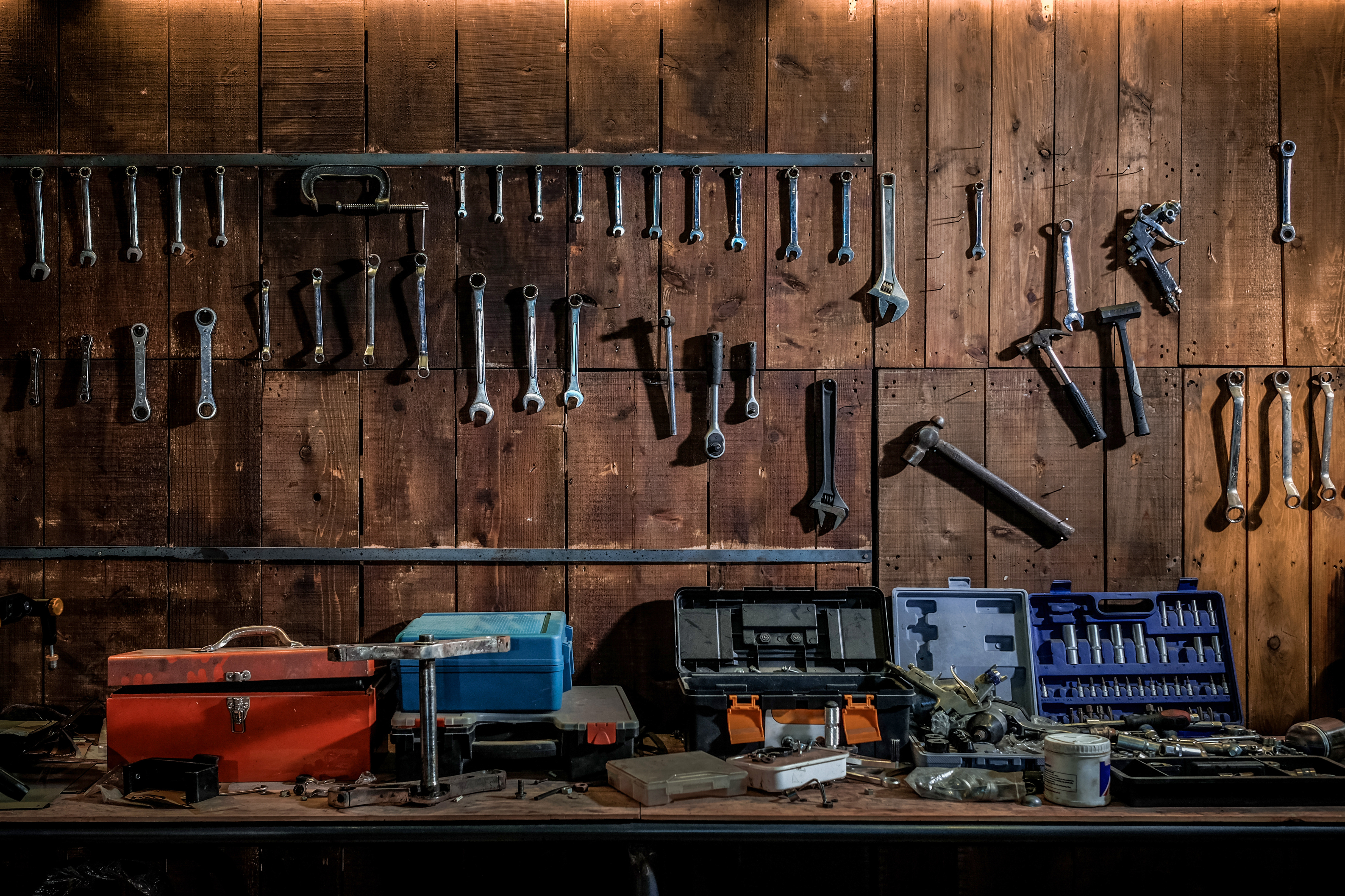 Workshop scene. Old tools hanging on wall in workshop, Tool shelf against a table and wall, vintage garage style. | Source: Shutterstock