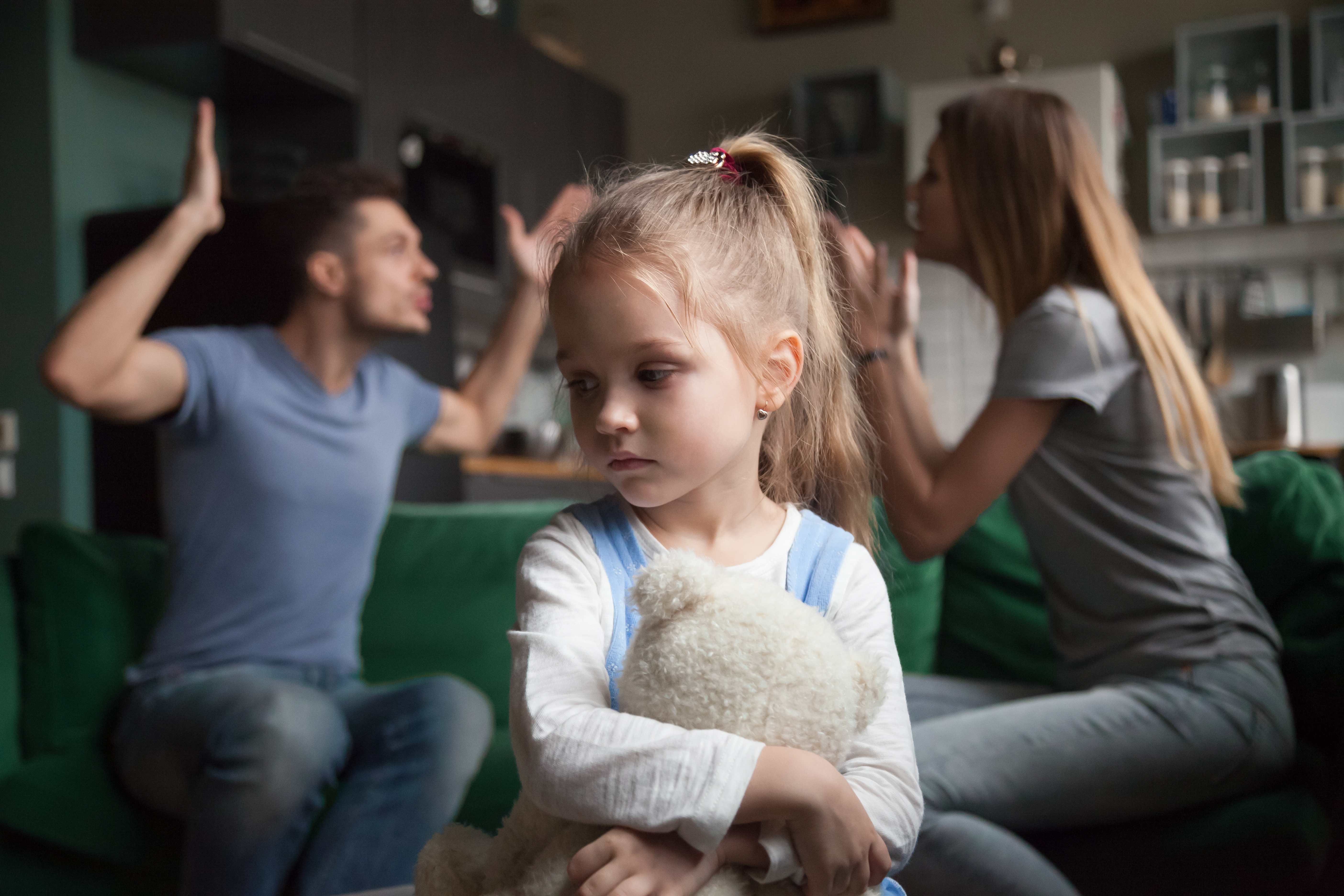 A little girl looking sad while a couple argues in the background | Source: Shutterstock