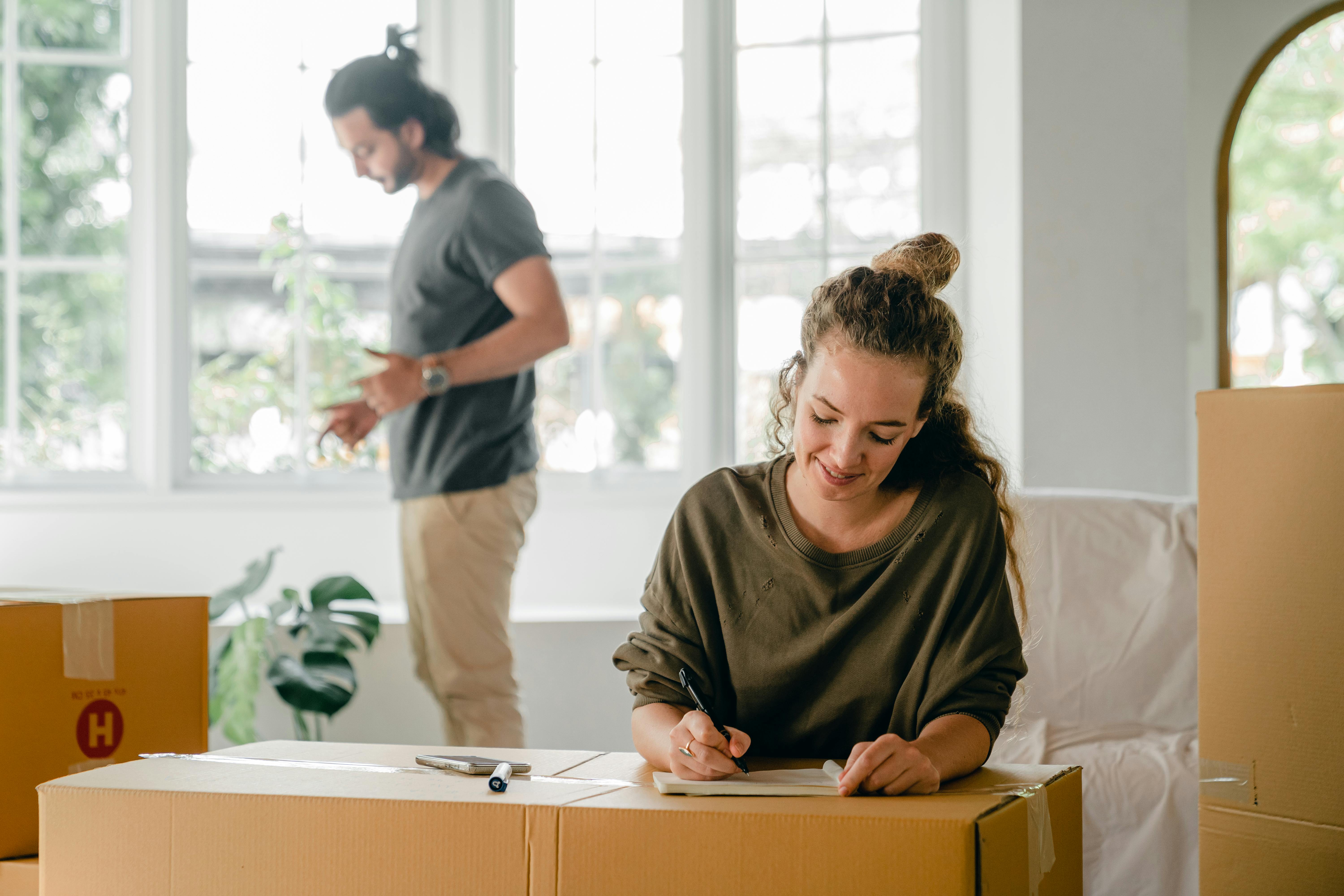 Man and woman moving into a new home, with the woman signing some papers | Source: Pexels