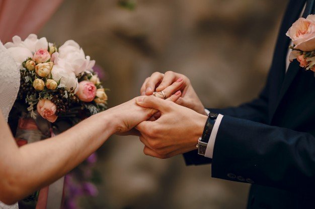 Groom slipping ring onto brides finger. | Photo: Freepik