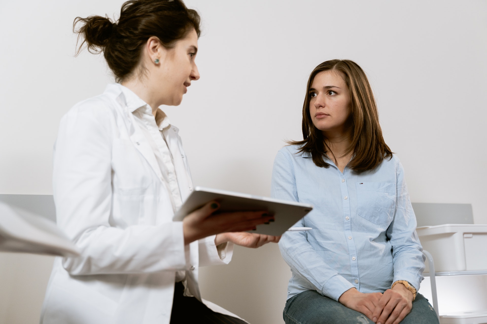 A woman in a white coat talking to a pregnant woman | Source: Pexels