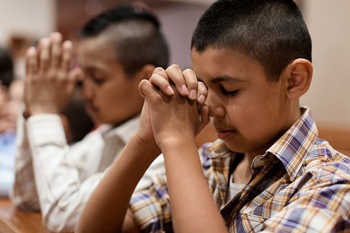 Photo of Hispanic boys praying in church | Photo: Getty Images