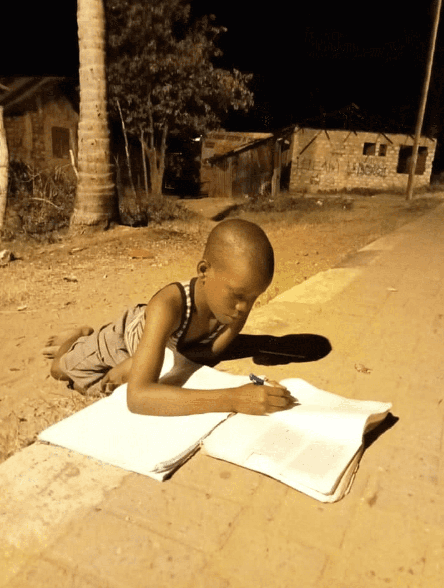 Kenyan boy doing his school homework on the streets. | Photo: Facebook/emruu1