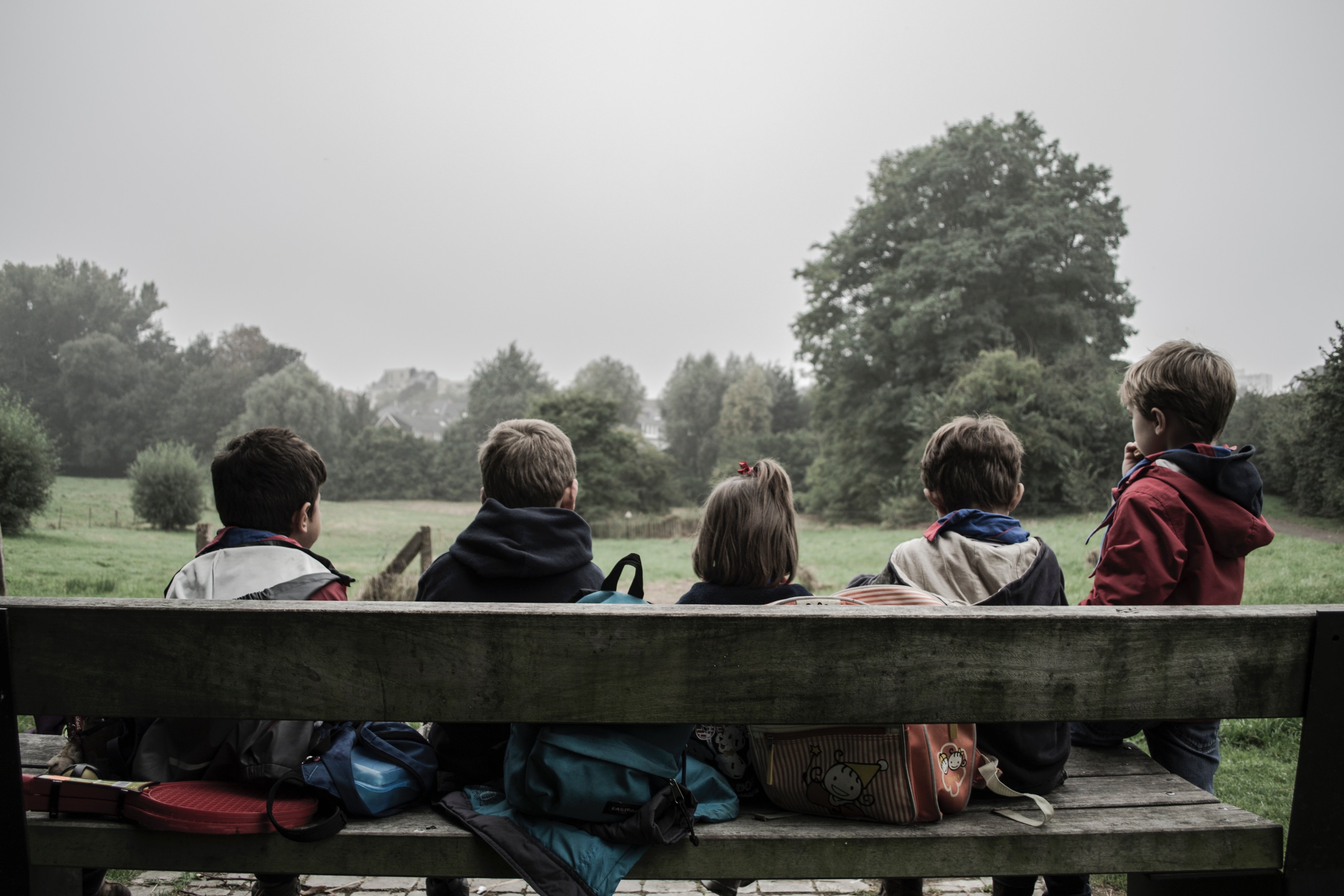 Five children sitting on a park bench. | Source: Unsplash