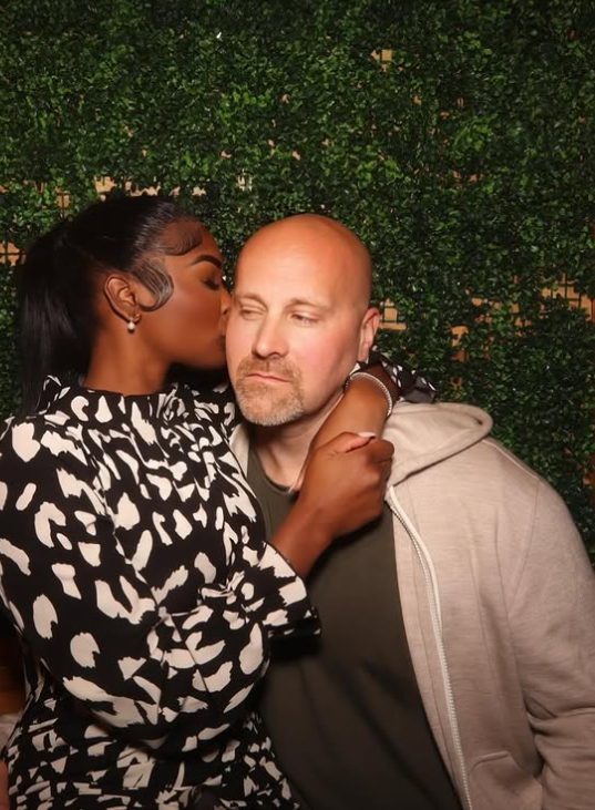 Ashly Robinson leans in to kiss Joe McCann’s cheek, her arm wrapped around him as he holds a calm, almost playful composure in the affectionate moment. | Source: Instagram/ashleejenae