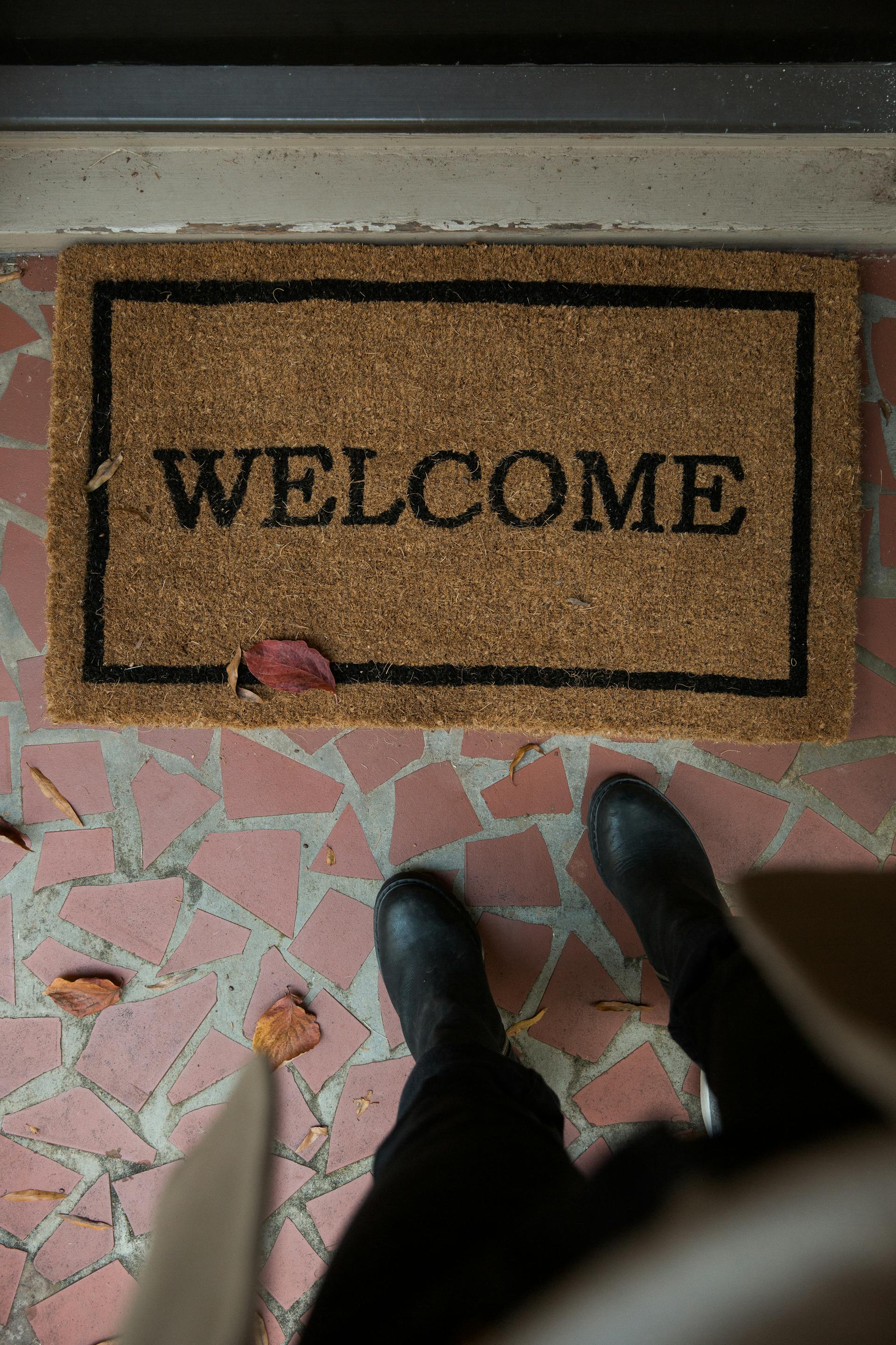 A person standing at a welcome mat | Source: Pexels