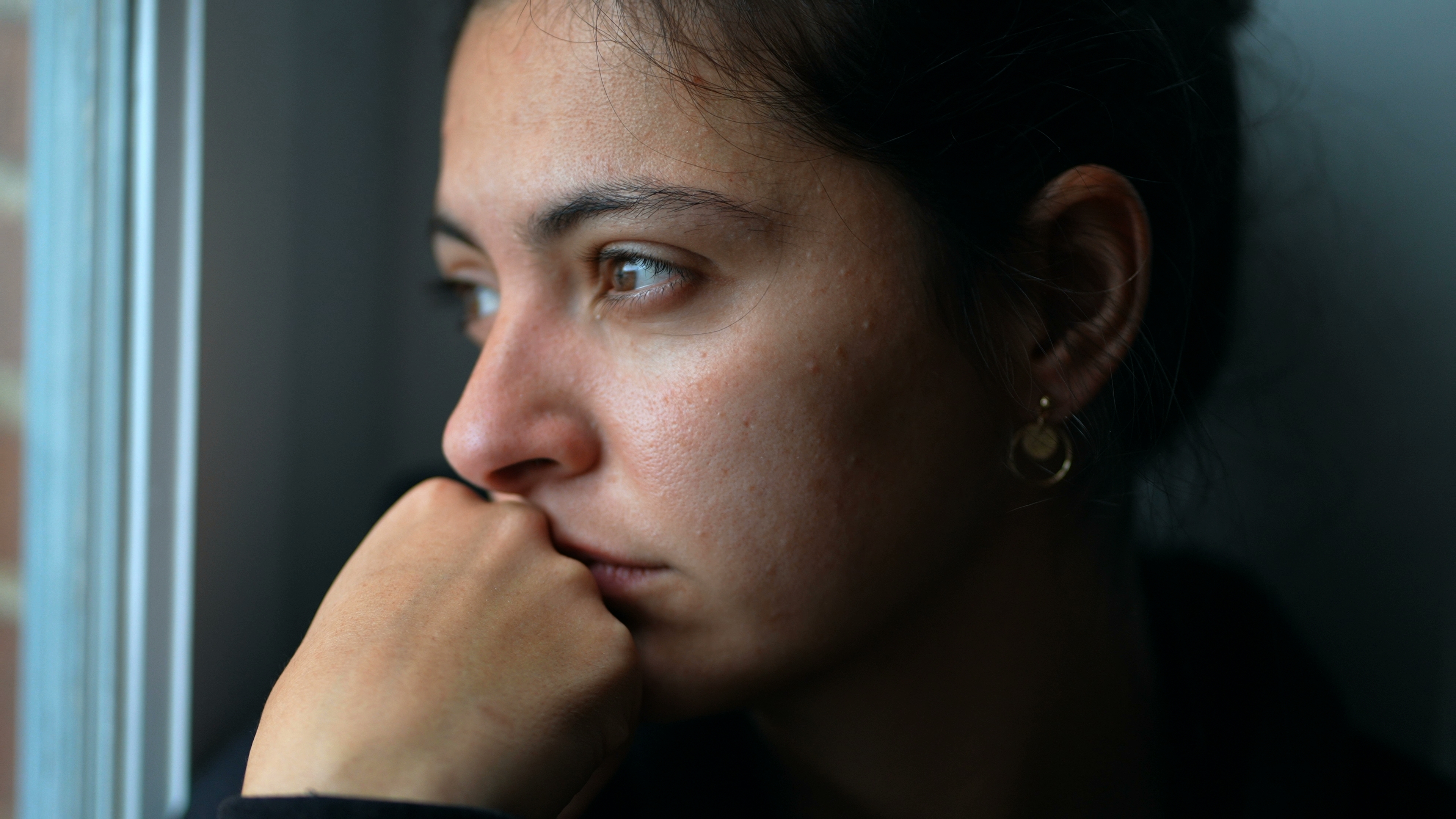 Une jeune femme perdue dans ses pensées en regardant par la fenêtre | Source : Shutterstock