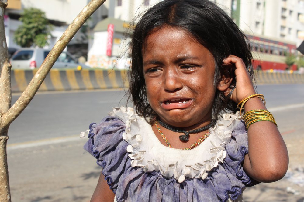 Beggar girl from India crying on the streetside. | Source: Shutterstock