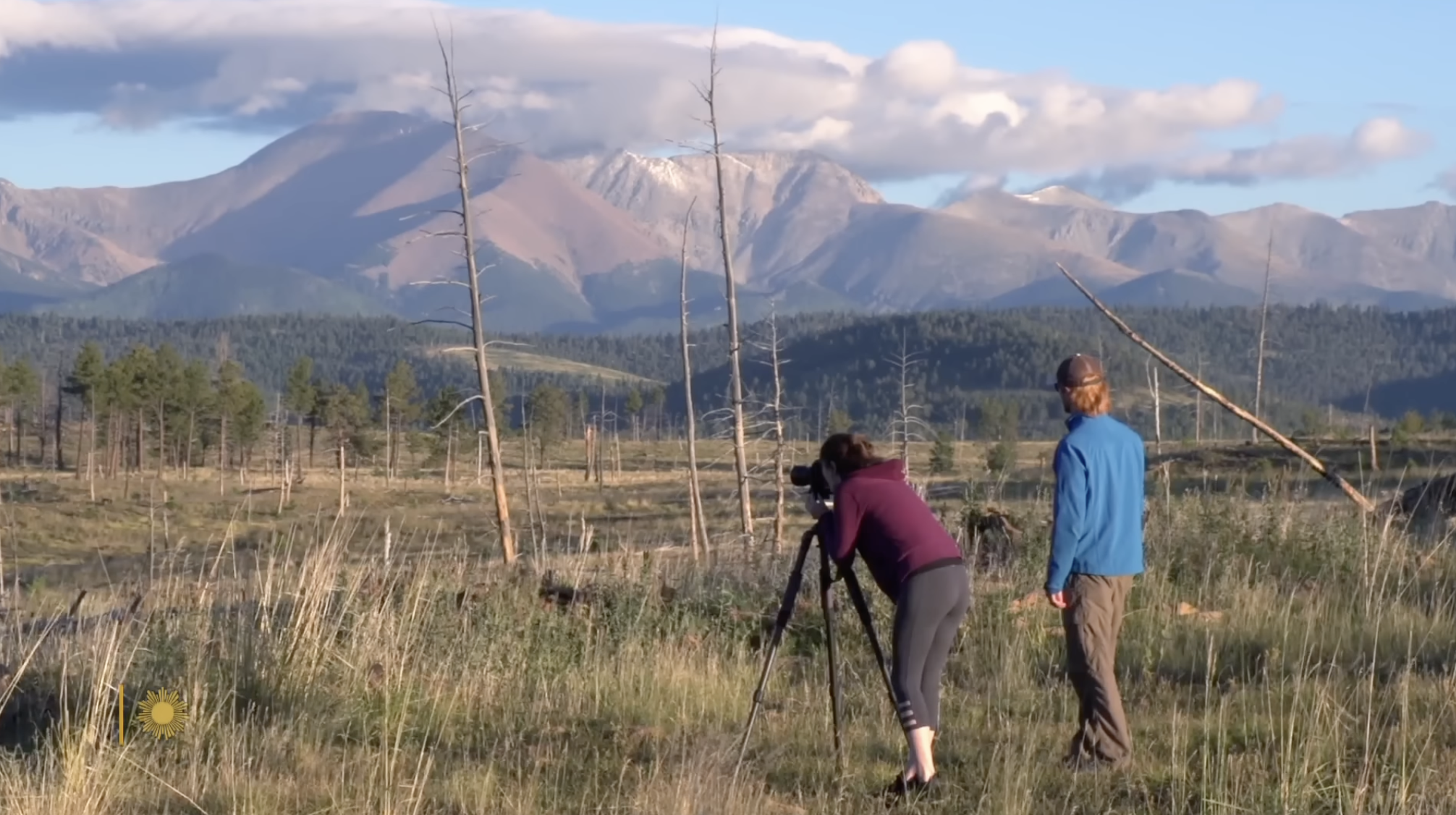 A photographer captures sweeping mountain landscapes at sunset while exploring the protected wilderness preserved across Turner’s ranch network. | Source: YouTube/CBS Sunday Morning