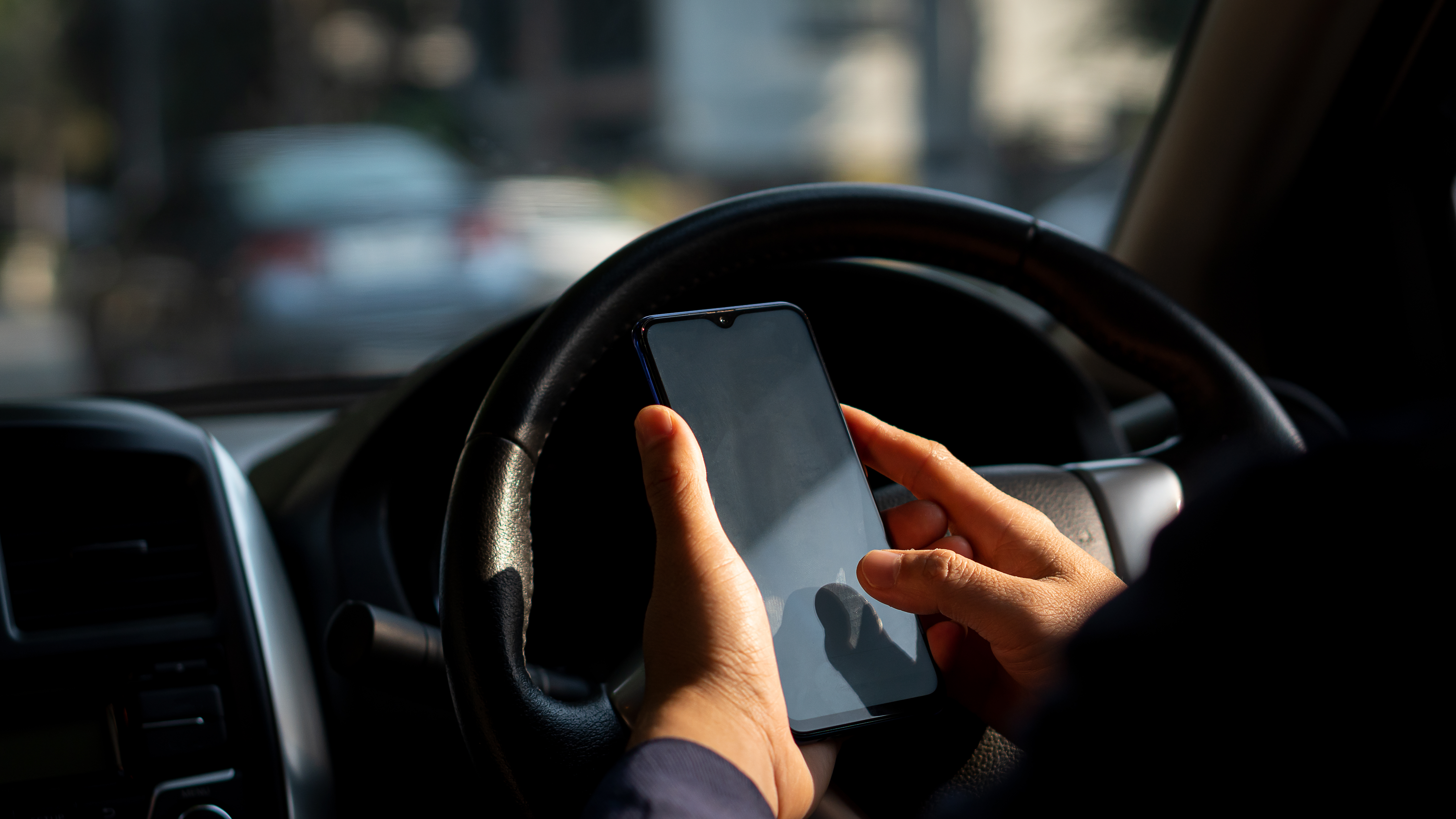 Picture of the driver's hand using a smart phone. | Source: Shutterstock