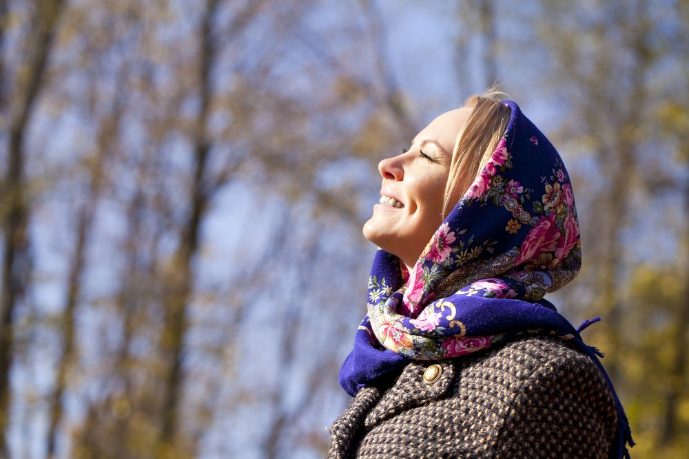 Mujer mira al cielo con una sonrisa de felicidad. | Foto: Shutterstock