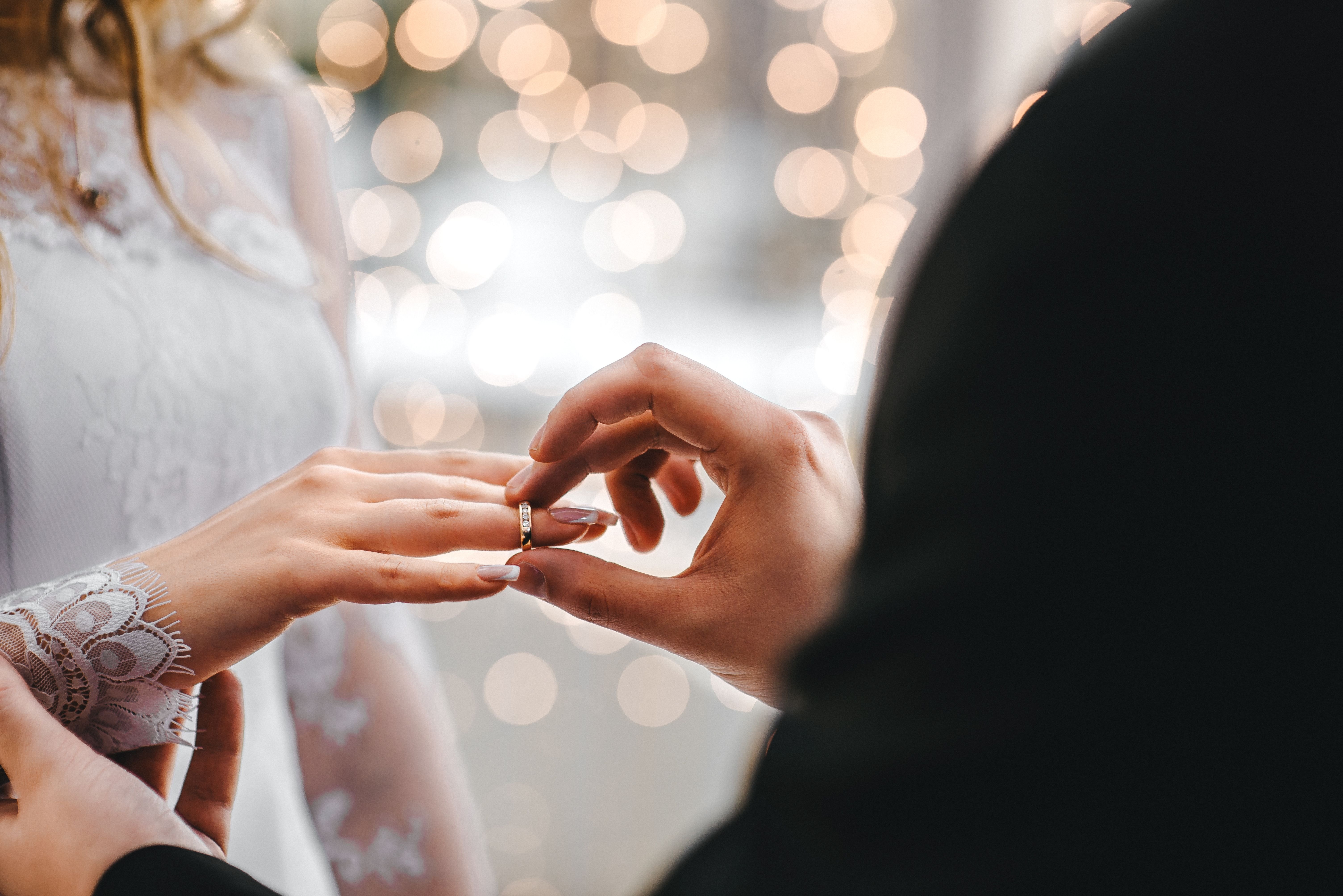 Ein Bräutigam, der einen Ehering an den Finger seiner Braut legt. | Quelle: Shutterstock
