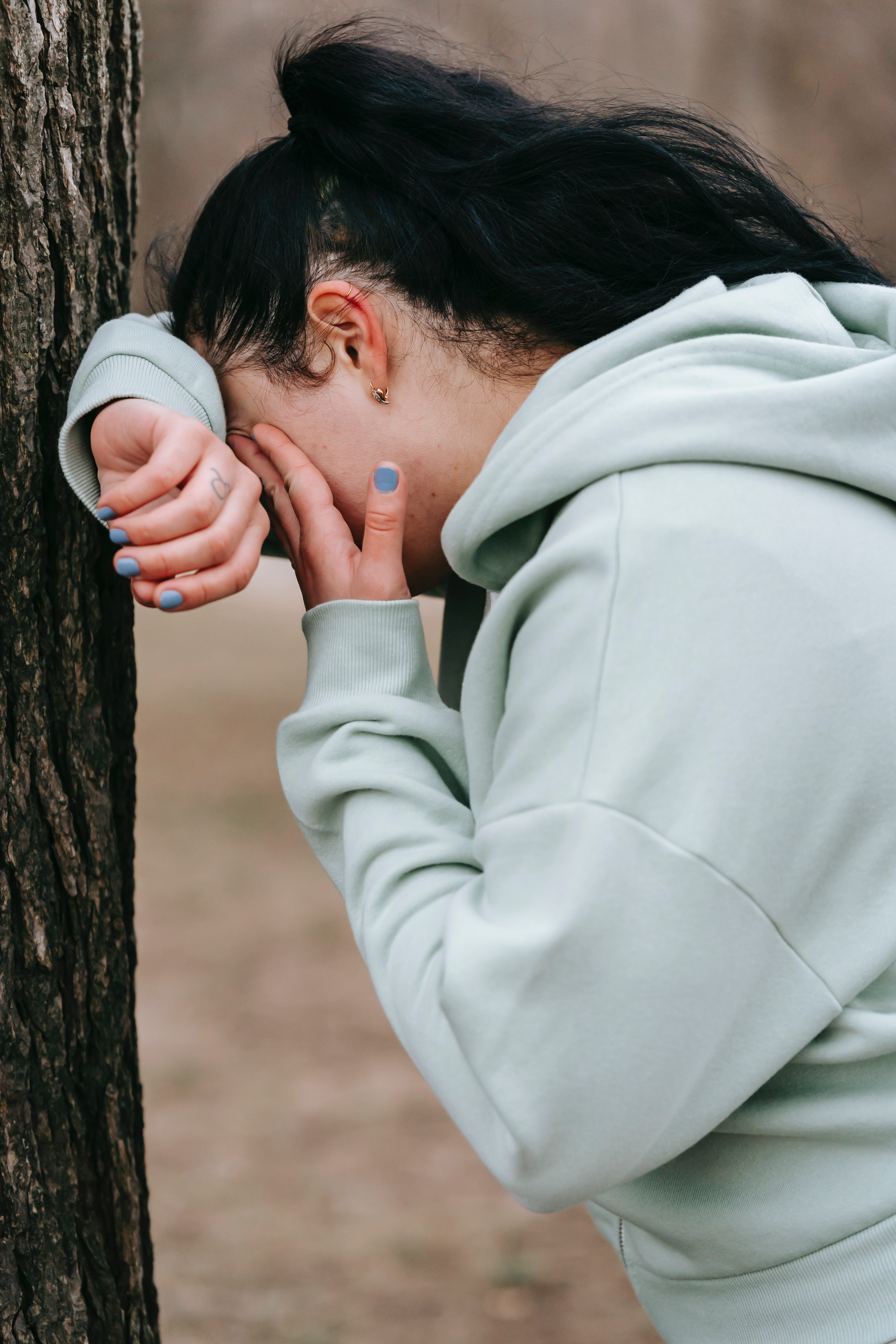 Unhappy woman leaning against a tree and crying | Quelle: Pexels