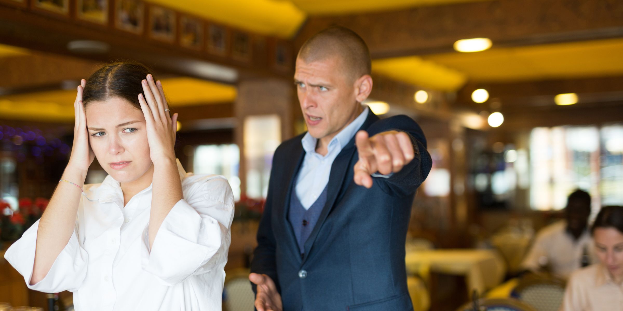 An angry man yelling at a young waitress | Source: Shutterstock