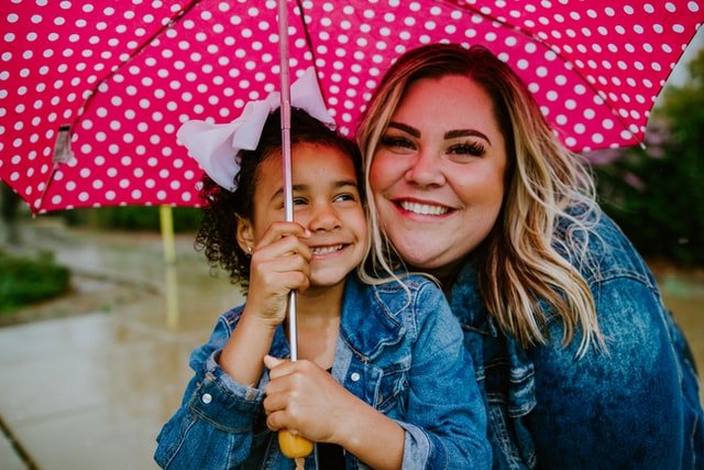 Woman and child smiling under an umbrella | Source: Unsplash