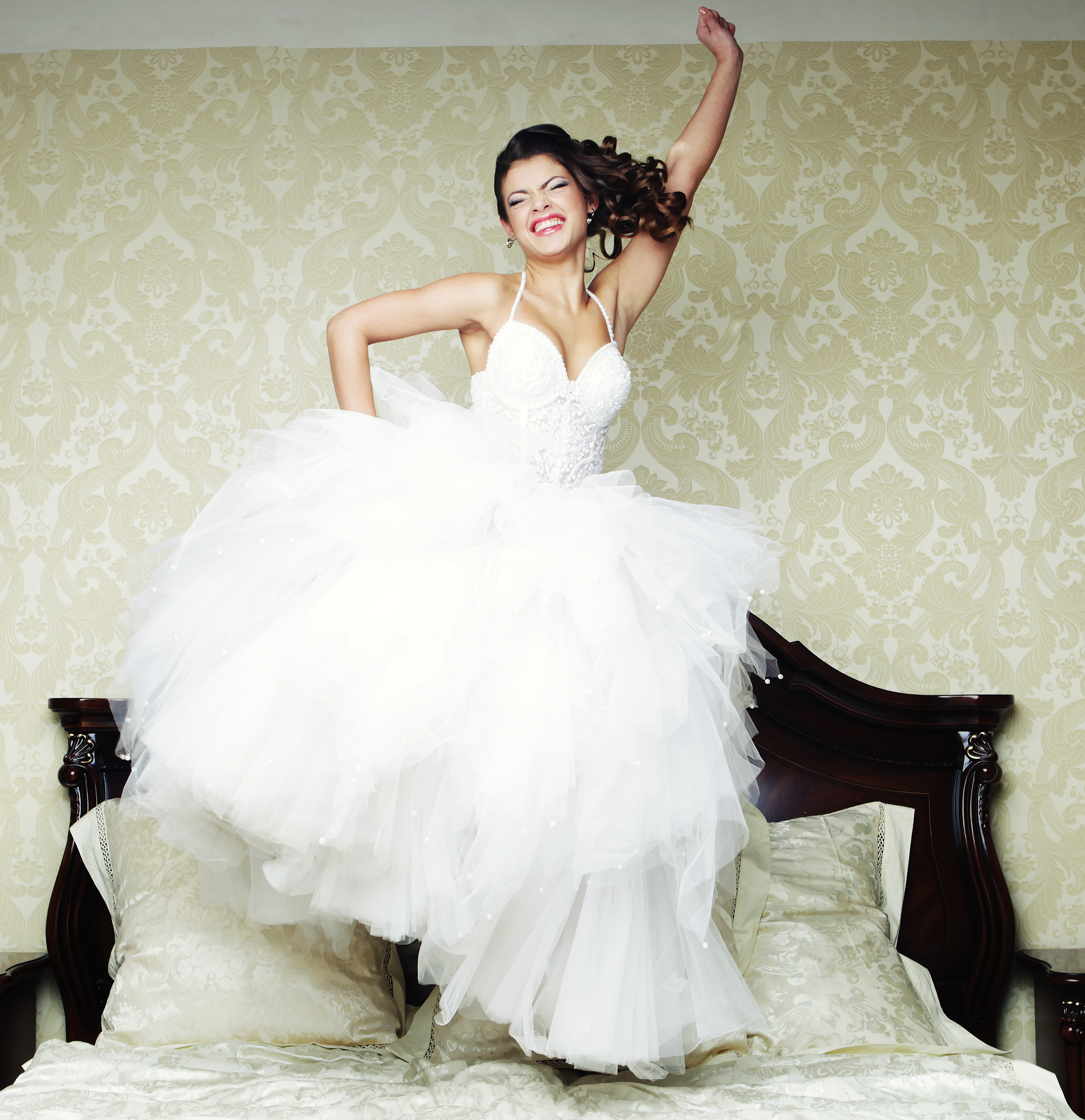 A happy bride jumping on a bed | Source: Shutterstock