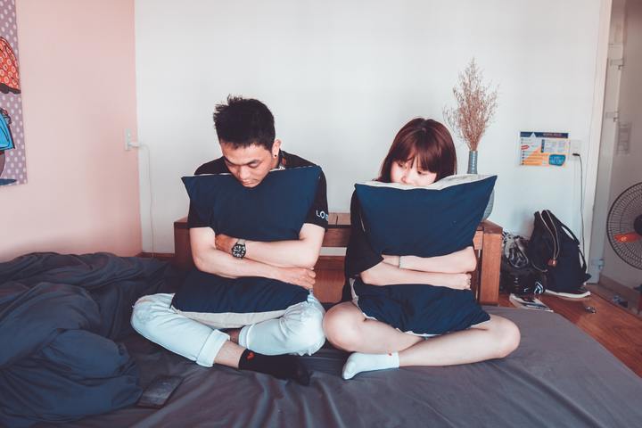 Pareja enfadada abraza almohadones. | Foto: Pxhere
