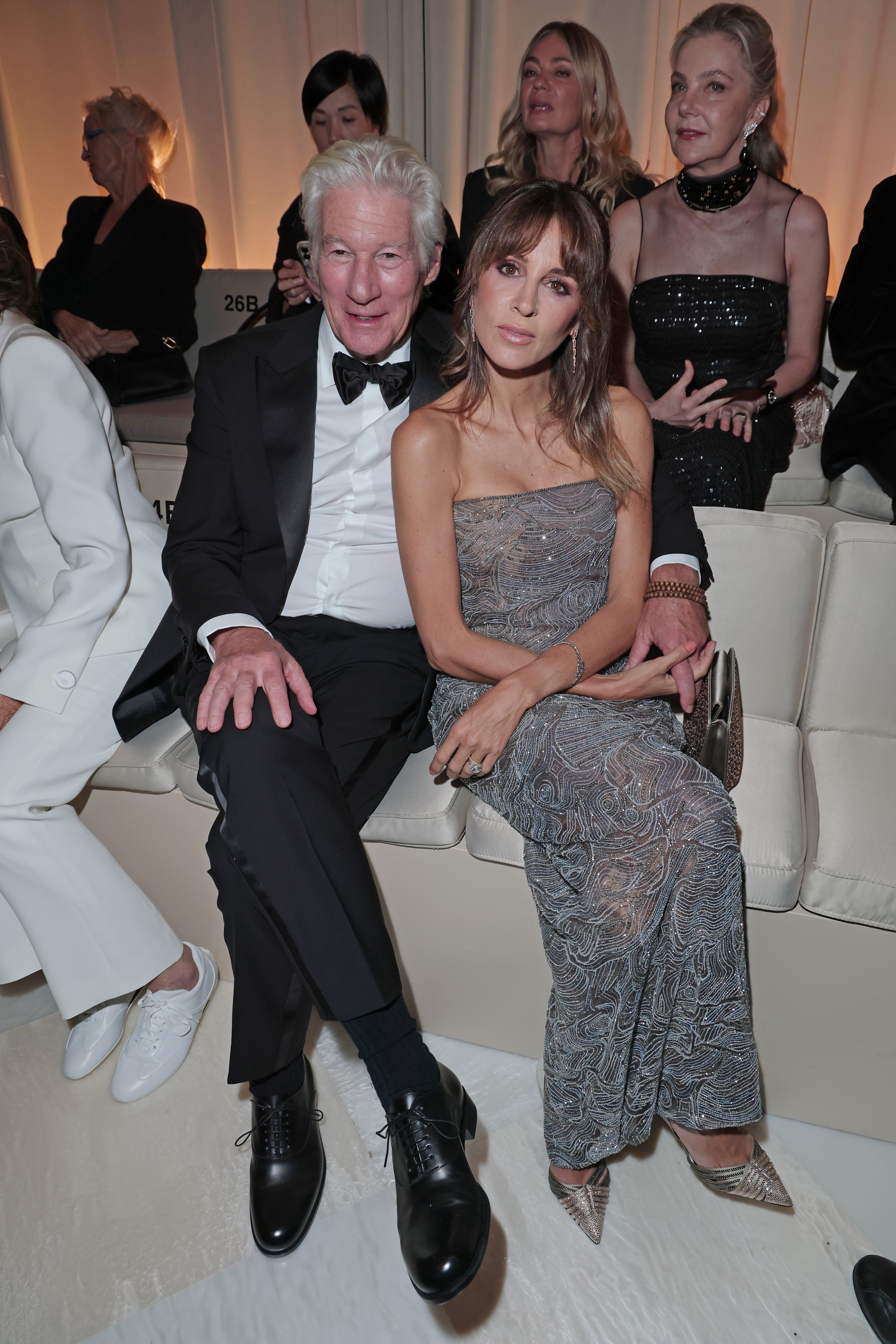 Alejandra Silva crosses her legs and leans forward as Richard Gere relaxes beside her, both locked in focus as the lights dim for the show to begin.