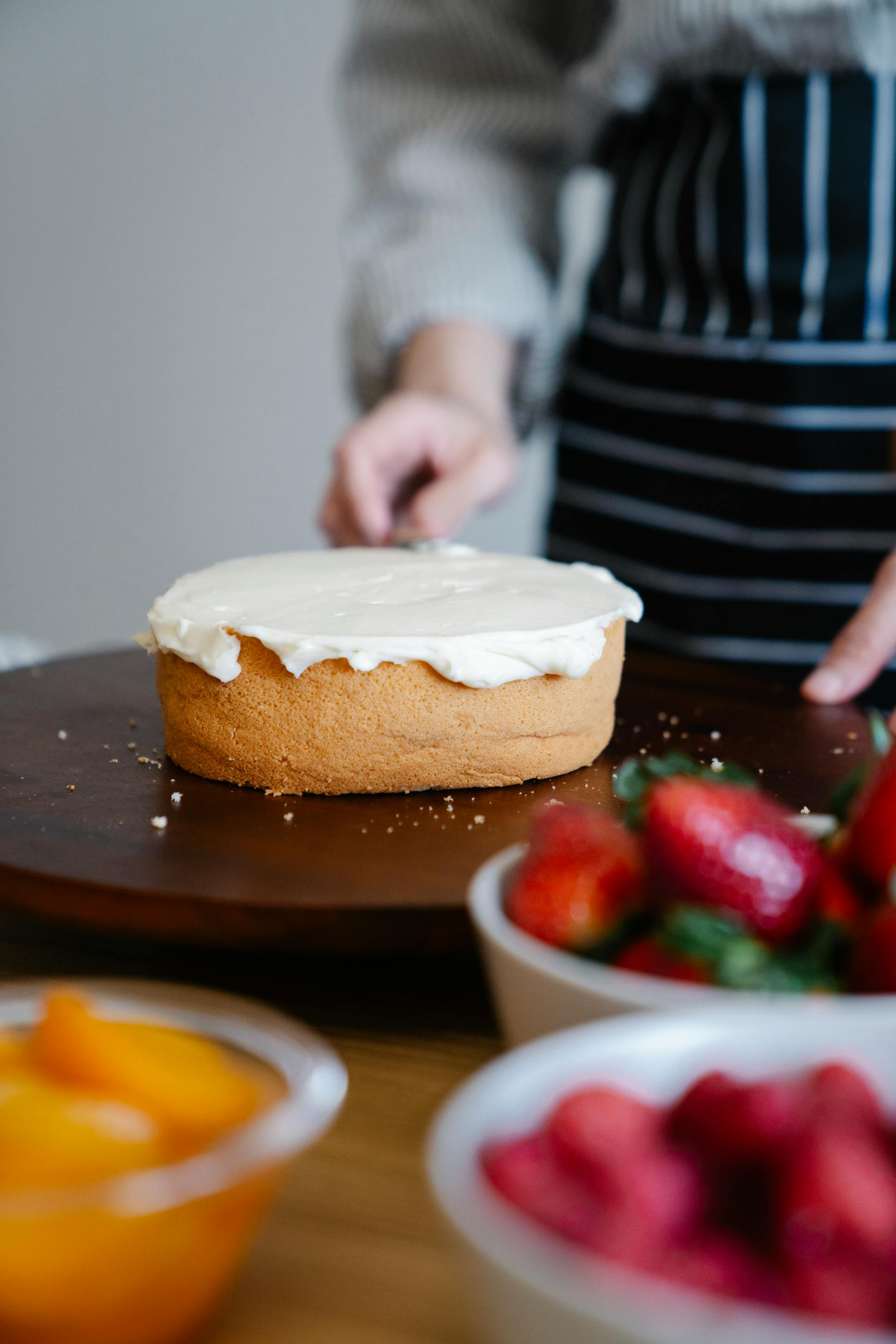 A woman putting the icing on a cake | Source: Pexels